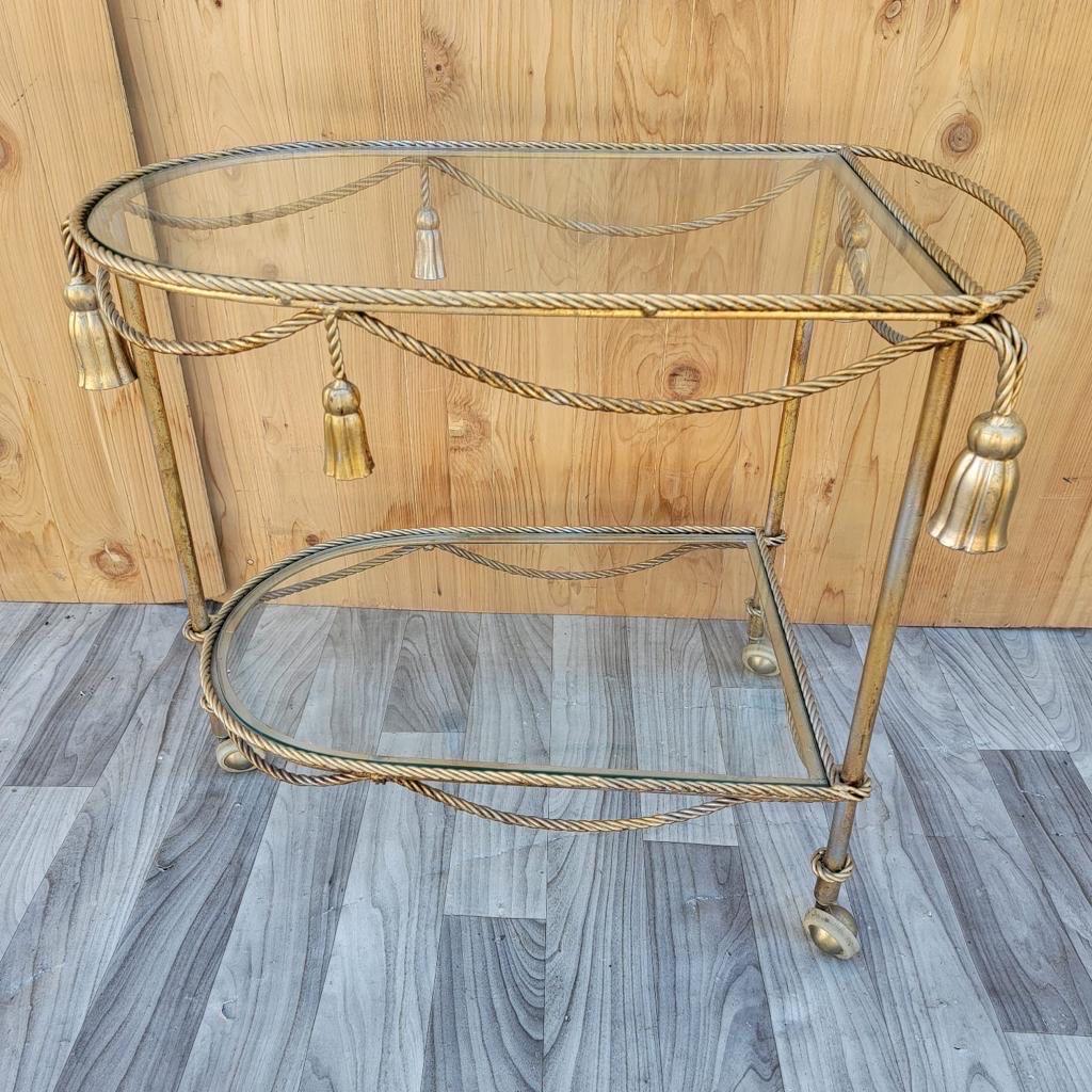 Vintage Hollywood Regency Italian Gilt Rope & tassle drinks trolley bar cart

This fabulous Italian mid century Hollywood Regency gilt-tole drinks trolley with gold twisted rope and tassel details. 

Circa 1970

Measures: H 25”
W 30”
D 17”.