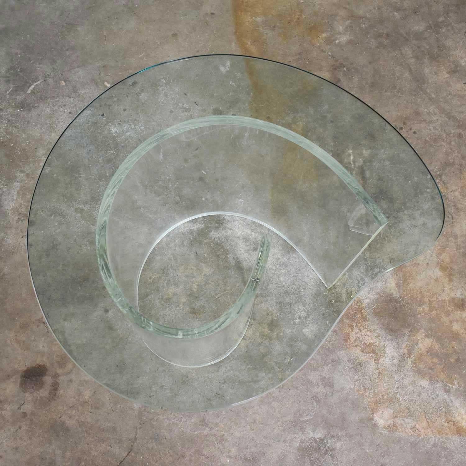Striking vintage Hollywood Regency Lucite snail or spiral end or side table with a kidney shaped glass top. The Lucite is in wonderful condition clear and with only small minor age appropriate scratches. The fabulous kidney shaped glass