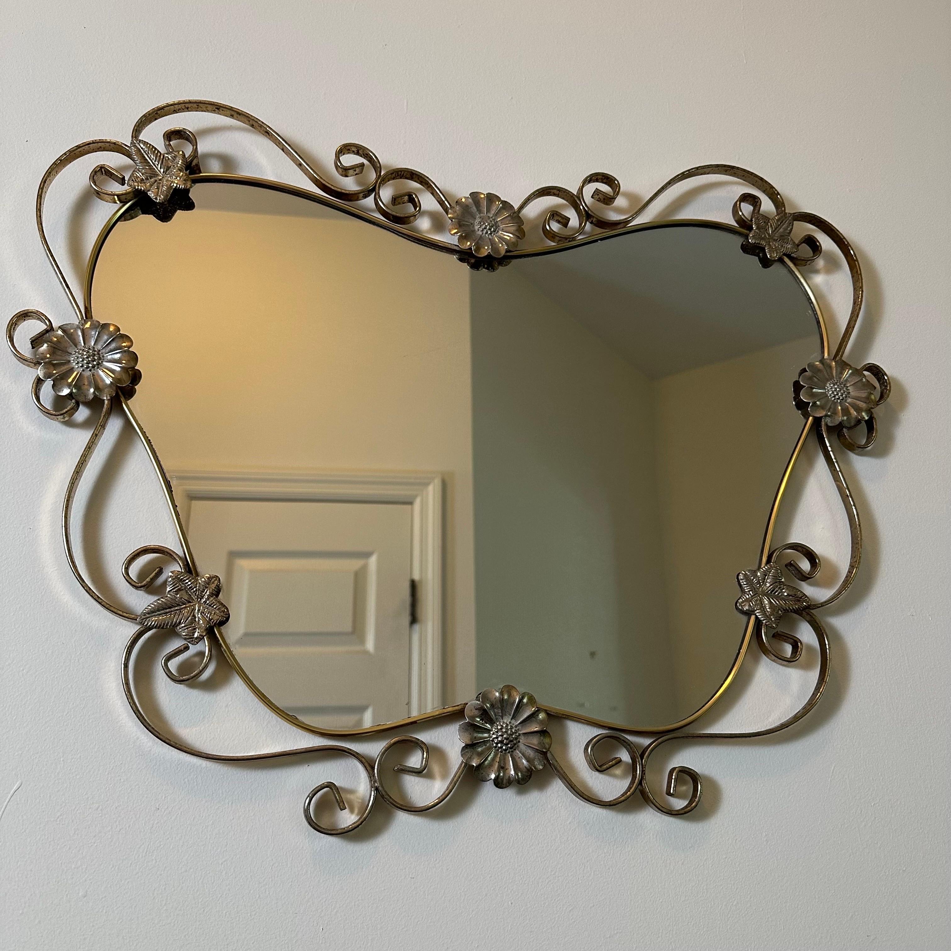 Beautiful Hollywood Regency mirror with two-tone metal finish, with steel and brass plate. The mirror itself is a butterfly shape, framed by an undulating border of flowers, vines, leaves, scrolls and swags. Unique, charming and feminine. Ready to