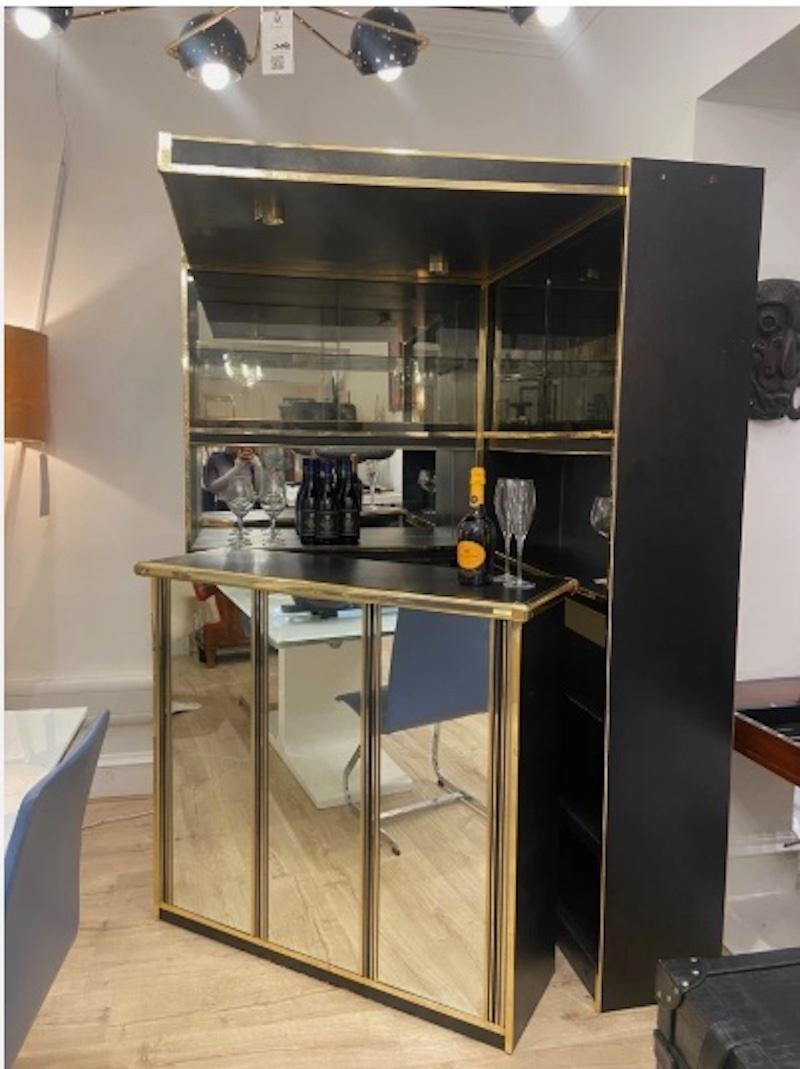 Add instant glamour into your entertaining space with this vintage Hollywood Regency-style bar, a stunning piece that captures the decadence and charm of mid-20th century design. 

With its sleek black finish, mirrored panels, and striking brass
