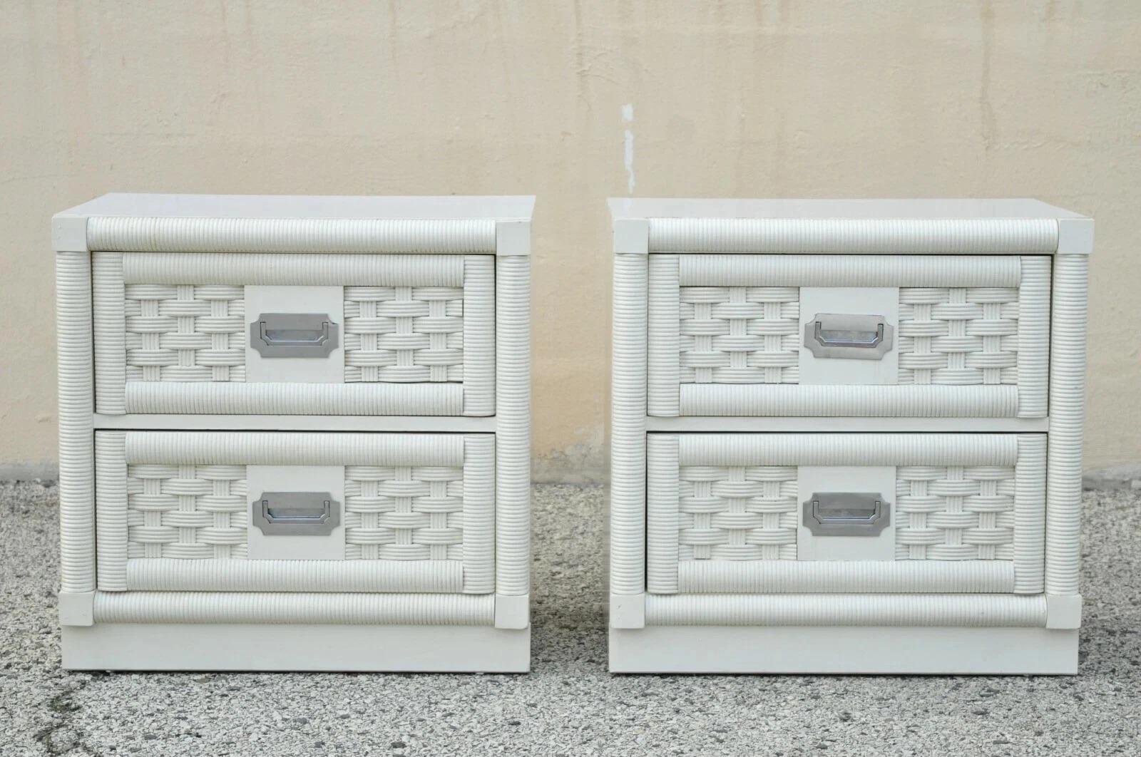 Vintage Hollywood Regency White Rattan Campaign Style Nightstands by Dixie - a Pair. Item features a laminate top, chrome campaign style handles, 2 dovetailed drawers, rattan and cane front, white/cream lacquer finish, quality American