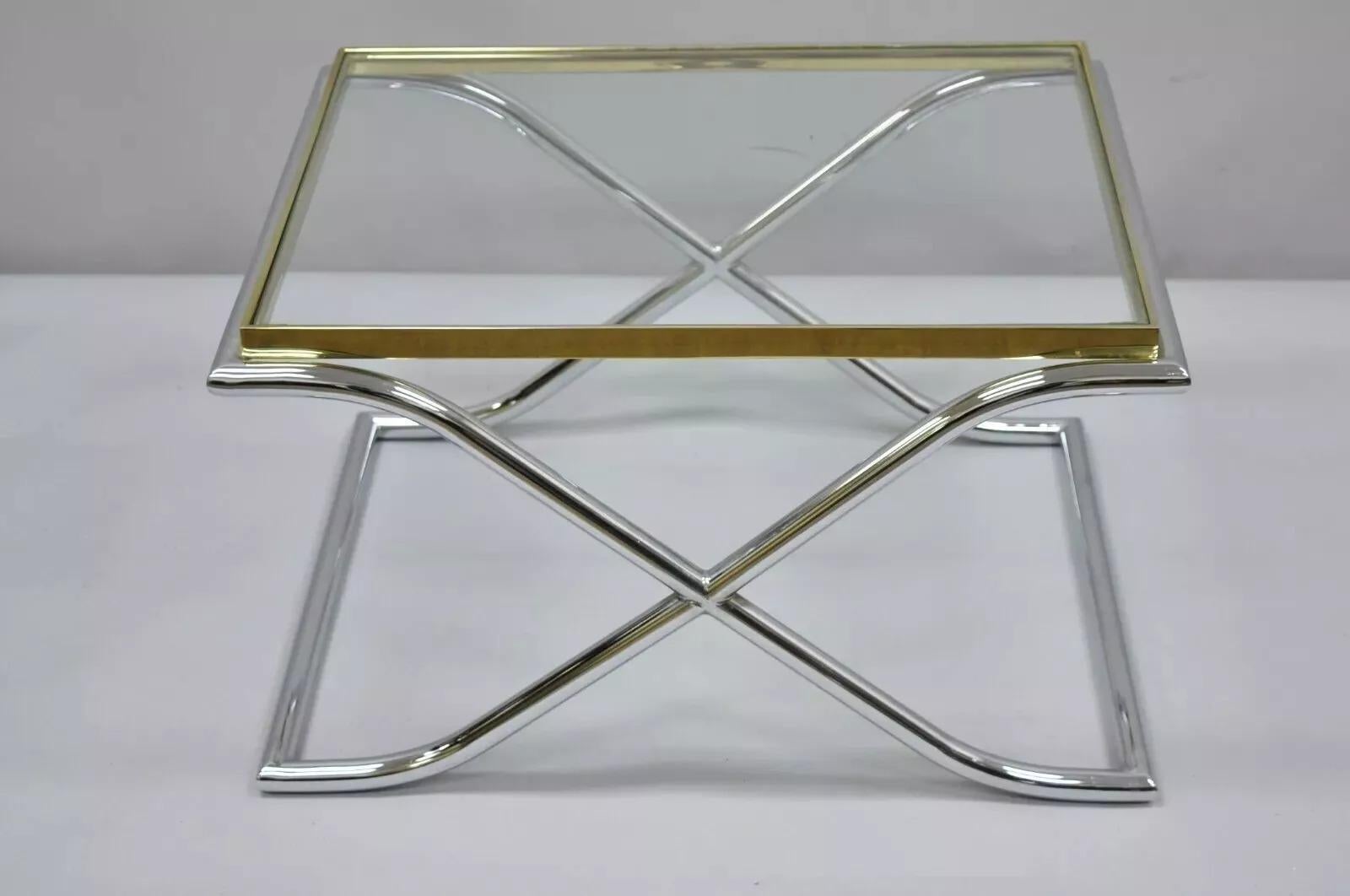 Vintage Chrome Brass and Glass Hollywood Regency X-Frame Small Coffee Table. Item features a chrome X- frame base, brass rim, inset glass top, great style and form. Circa Late 20th Century. Measurements: 16.5