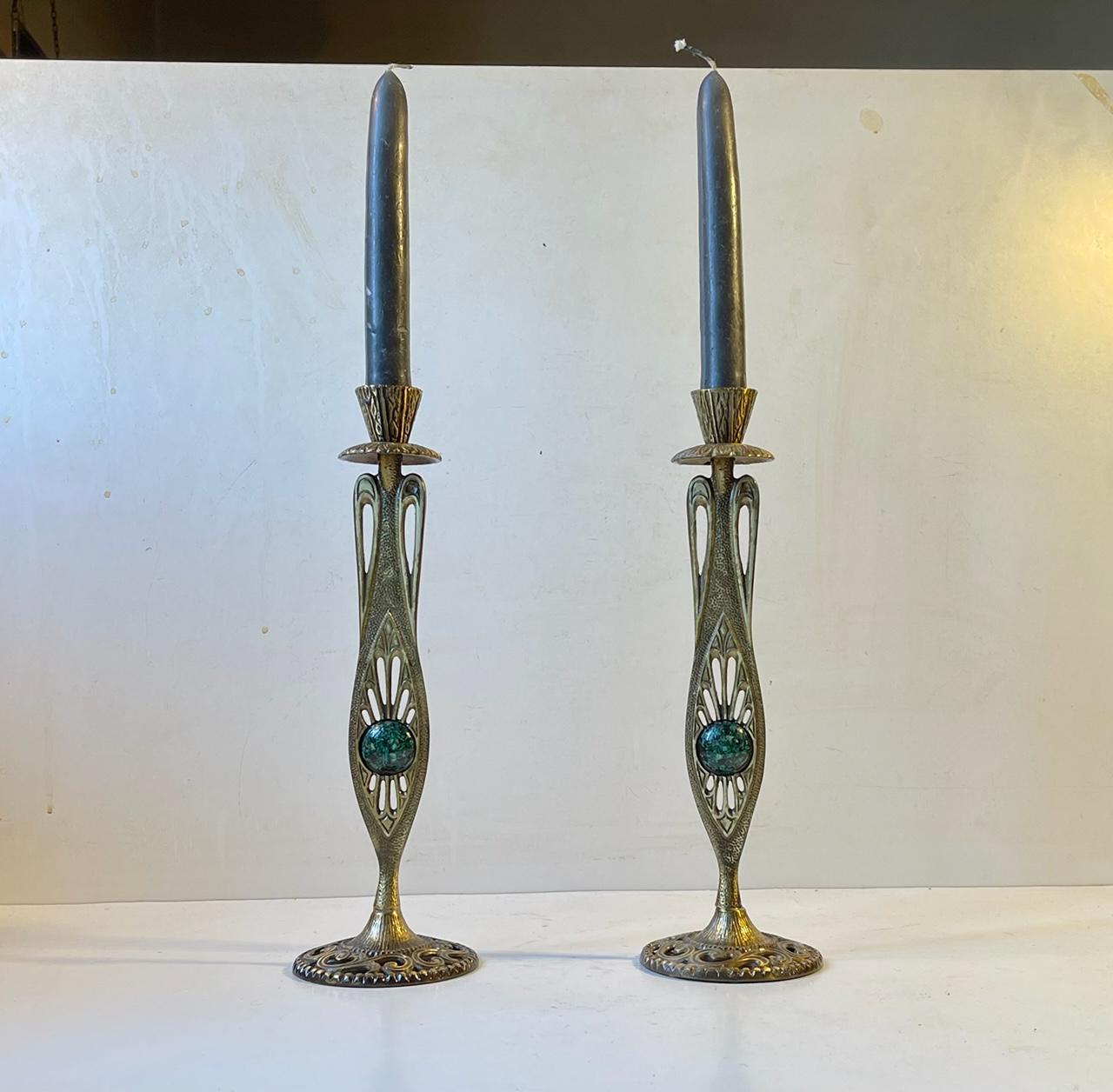 A pair of Art Nouveau / Arts & Crafts styled israeli candlesticks in cast ornamented and partially perforated brass. Set with polished oval pieces of Eliat. The Eilat stone is the name for a green inhomogeneous mixture of several secondary copper