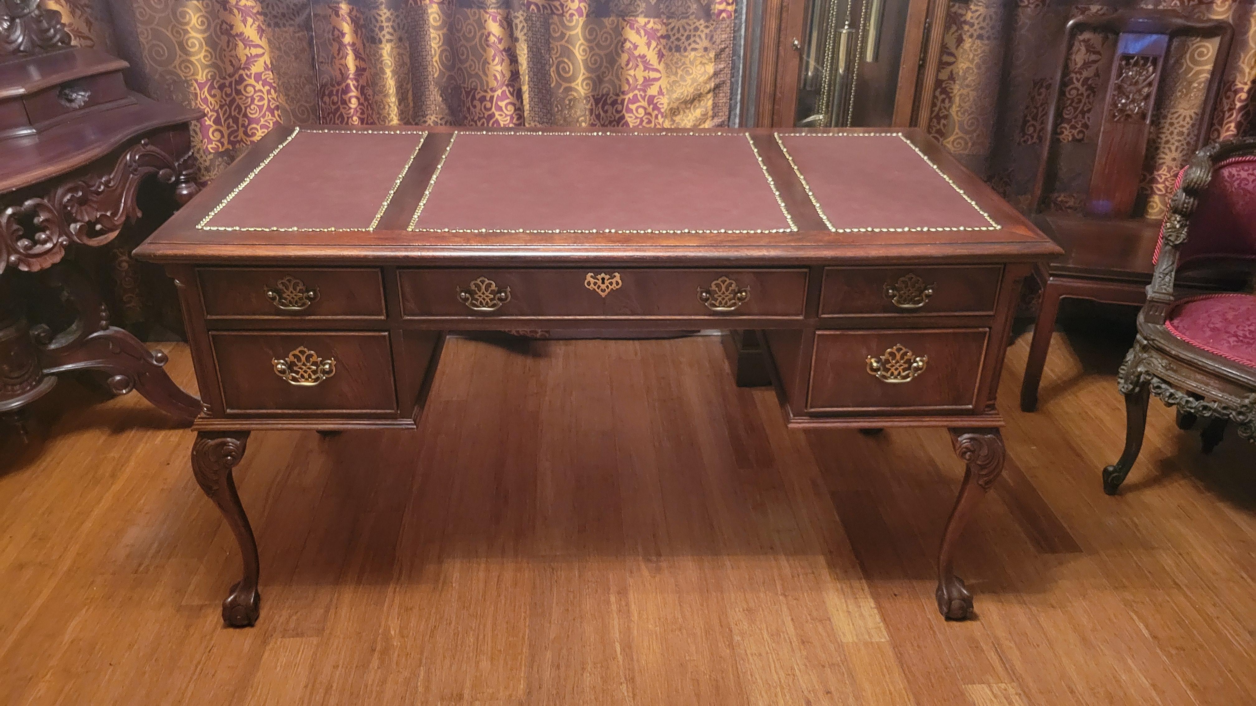 Antique style Hooker Furniture archivist desk. Made out of solid wood that looks like mahogany.
The top has three inserts in burgundy leather with brass trim. The desk has 5 drawers. It's 56