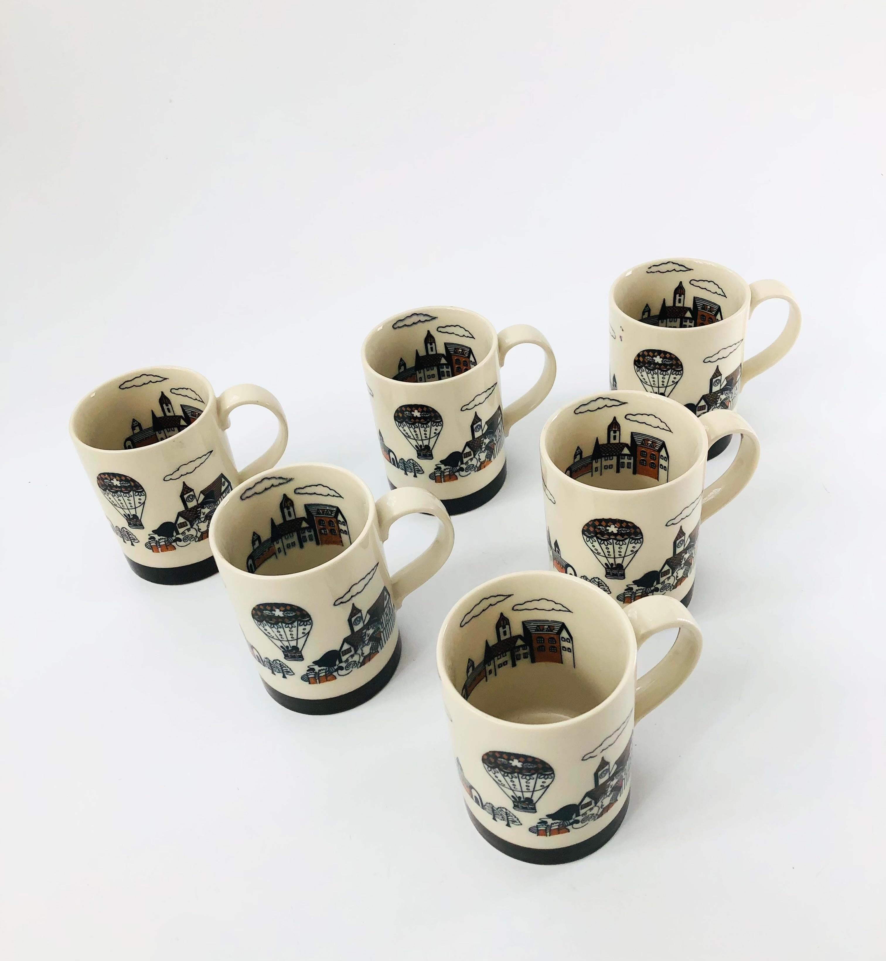 A set of 6 vintage ceramic mugs. Each features a sweet design of a town, hot air balloon, and a group of spectators in the foreground. A sweet view of the town also decorates the inside on one side.

  