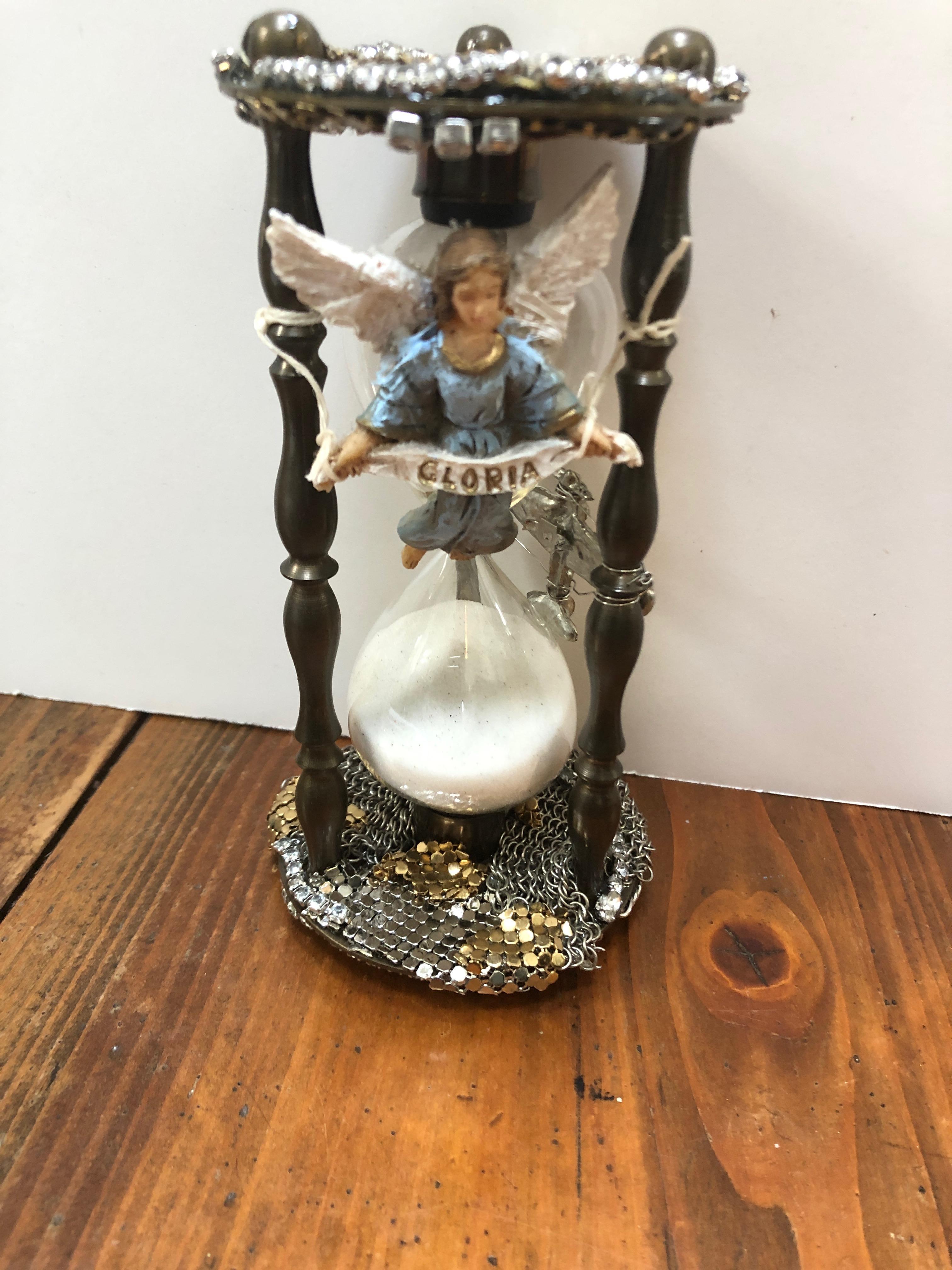 An extraordinary hourglass sculpture that's a visual poem to the notion of time passing, impermanence and the beauty of each moment. A multitude of powerful glittery overlapping media scavenged from vintage mesh purses, the angel from a Nativity,