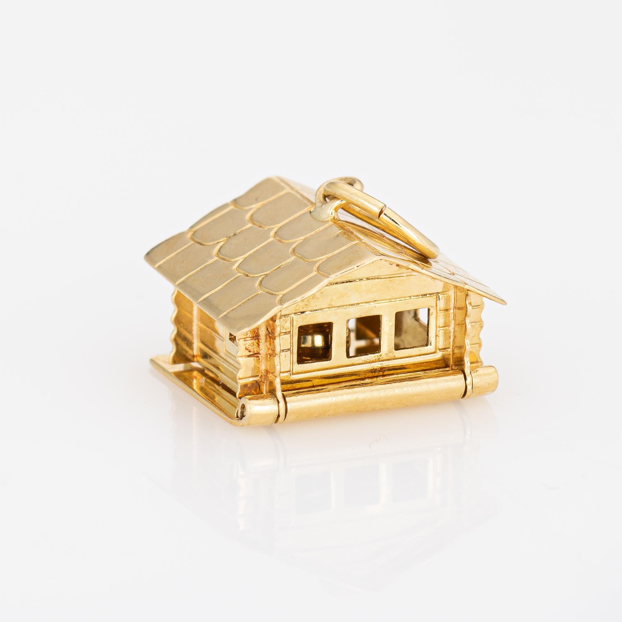 Finely detailed vintage house charm crafted in 18k yellow gold (circa 1950s to 1960s).  

The finely detailed house or cabin opens to reveal a suspended cooking pot (moves). Smaller in scale (1/2 inch diameter) the charm is great worn on a charm