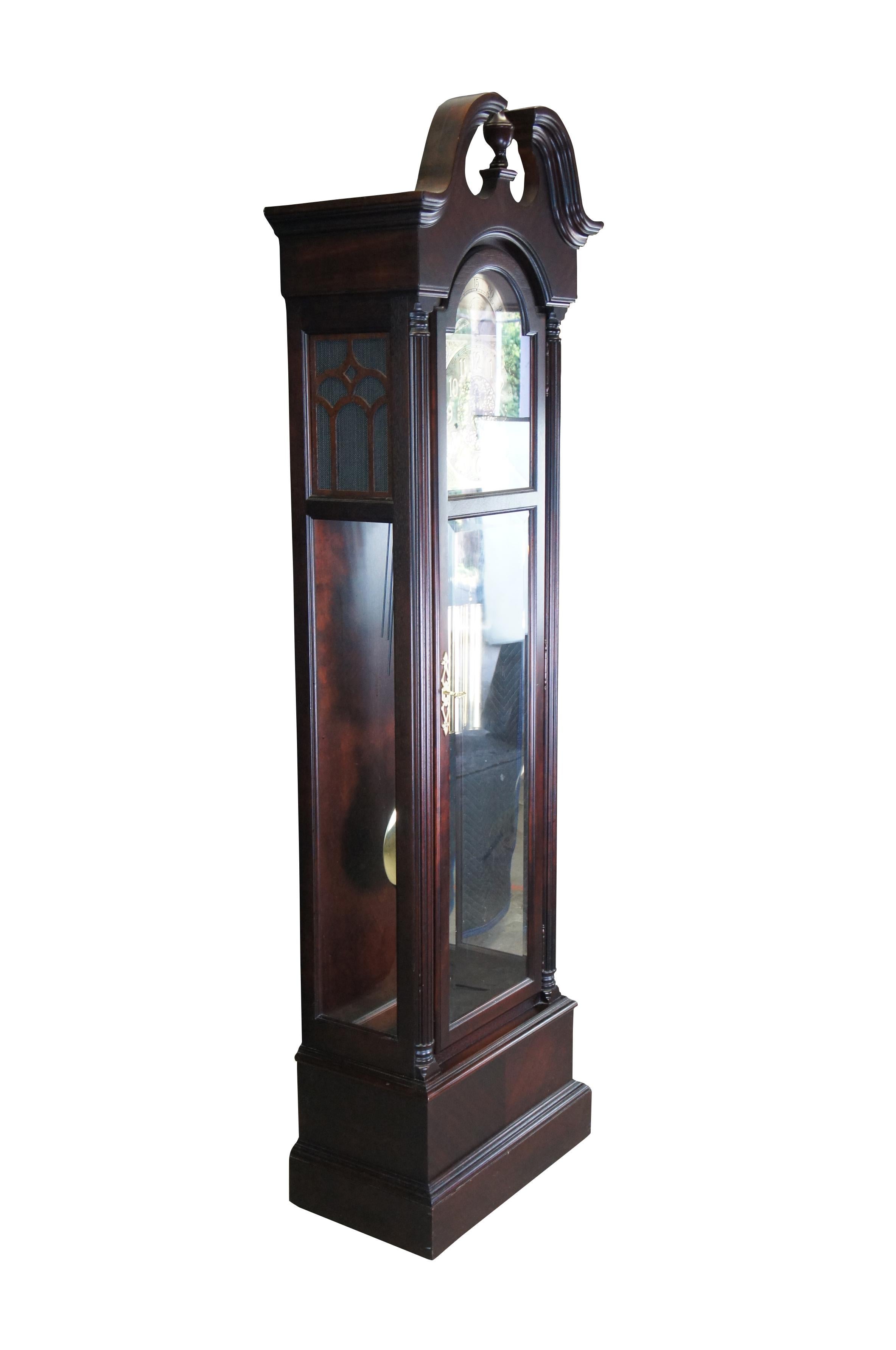 Late 20th century Howard Miller Grandfather Clock, serial number 609519.  Features a tall case made from mahogany with quarter cut reeded columns and an open pediment with central finial. Includes 3 chime settings.  Face is metal with filigree