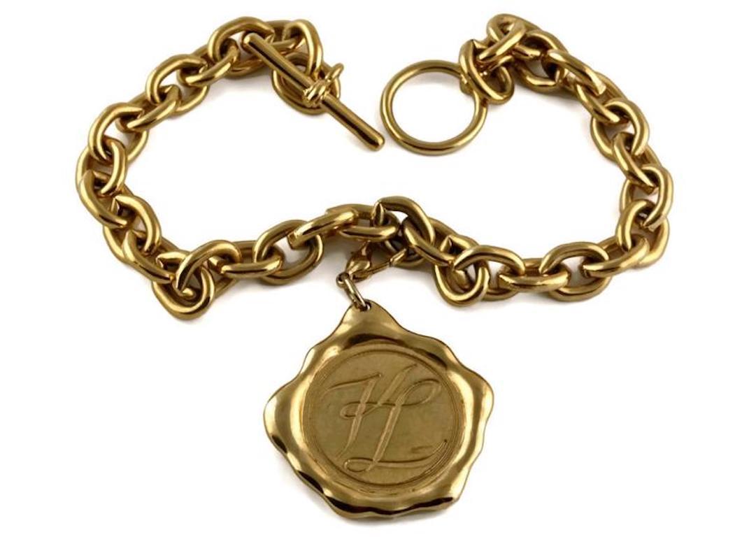 Vintage Huge KARL LAGERFELD Wax Seal Logo Coin Medallion Necklace

Measurements:
Medallion: 2 inches X 2 inches
Length: 15 2/8 inches

Features:
- 100% Authentic KARL LAGERFELD.
- Huge wax seal medallion pendant.
- Embossed KARL LAGERFELD PARIS and