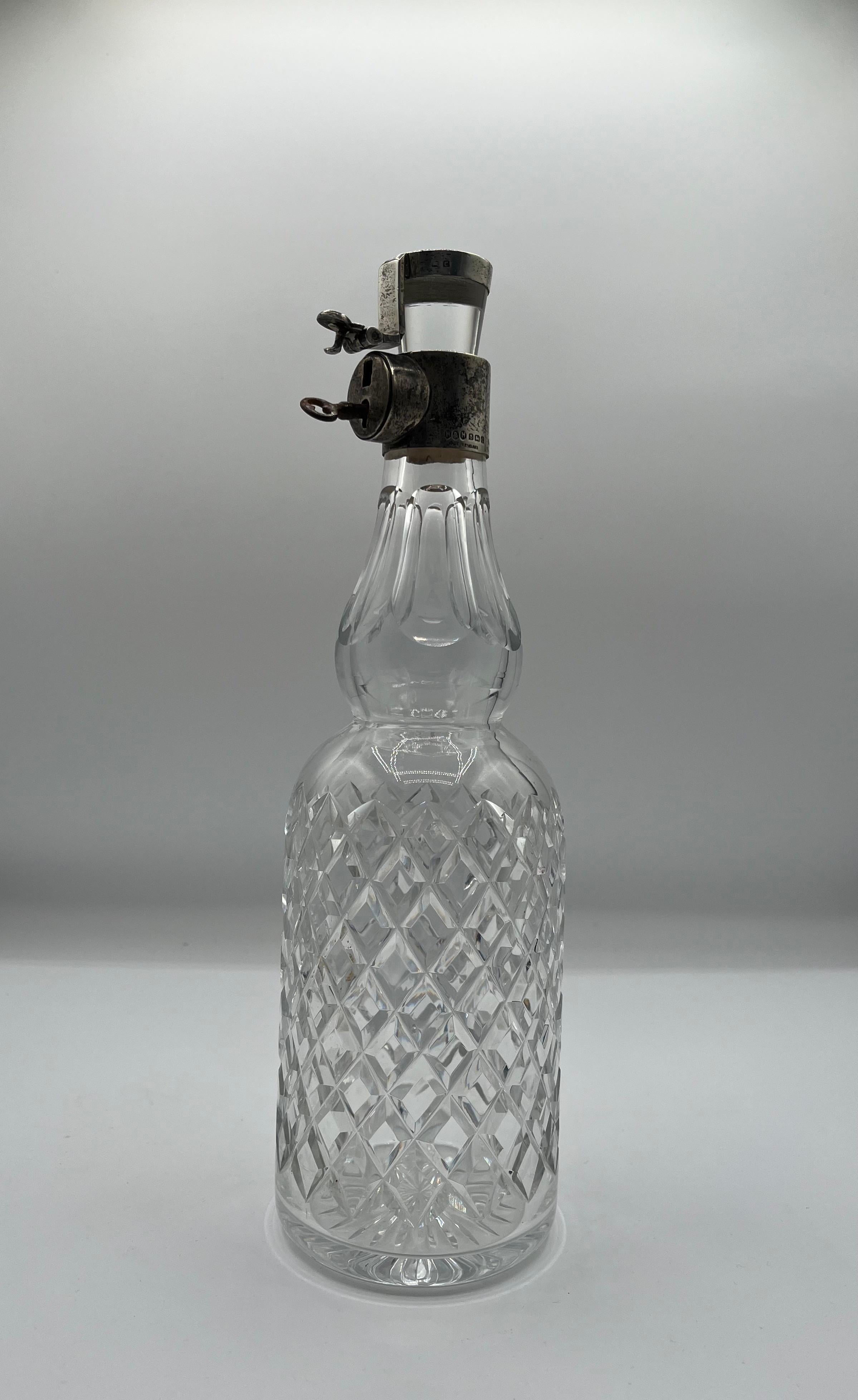 Beautiful glass locking decanter by Hukin & Heath. Sterling Silver collar, lock and cap. Full hallmarks include, an anchor denoting Birmingham, England. Lion, denoting Sterling Siver, and a C, denoting 1898.
