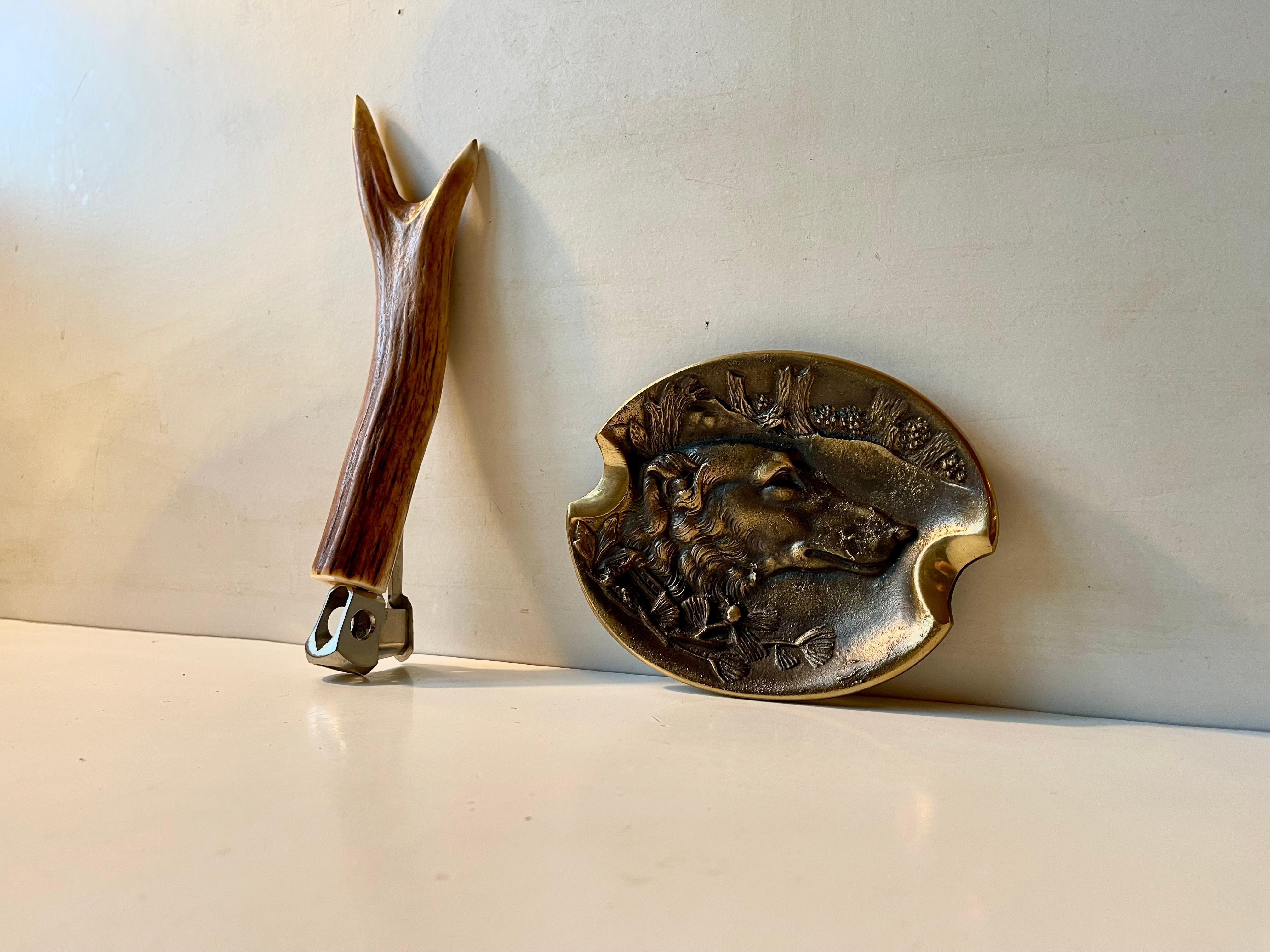 XL stag handled cigar cutter from Sollingen Germany circa 1950-60. Its accompanied by a stylish German made brass cigar ashtray with two large sleves and a motif of a hunting dog. Measurements: L: 24 cm, H: 4.5 cm (cigar cutter), the ashtray