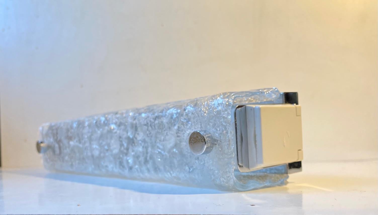 Large rectangular bathroom sconce composed of bend ice glass and chromed steel. It features 3 lightsources through 3 original porcelain sockets and it has a power outlet to one of its sides. We suspect this rather unusual version were commissioned