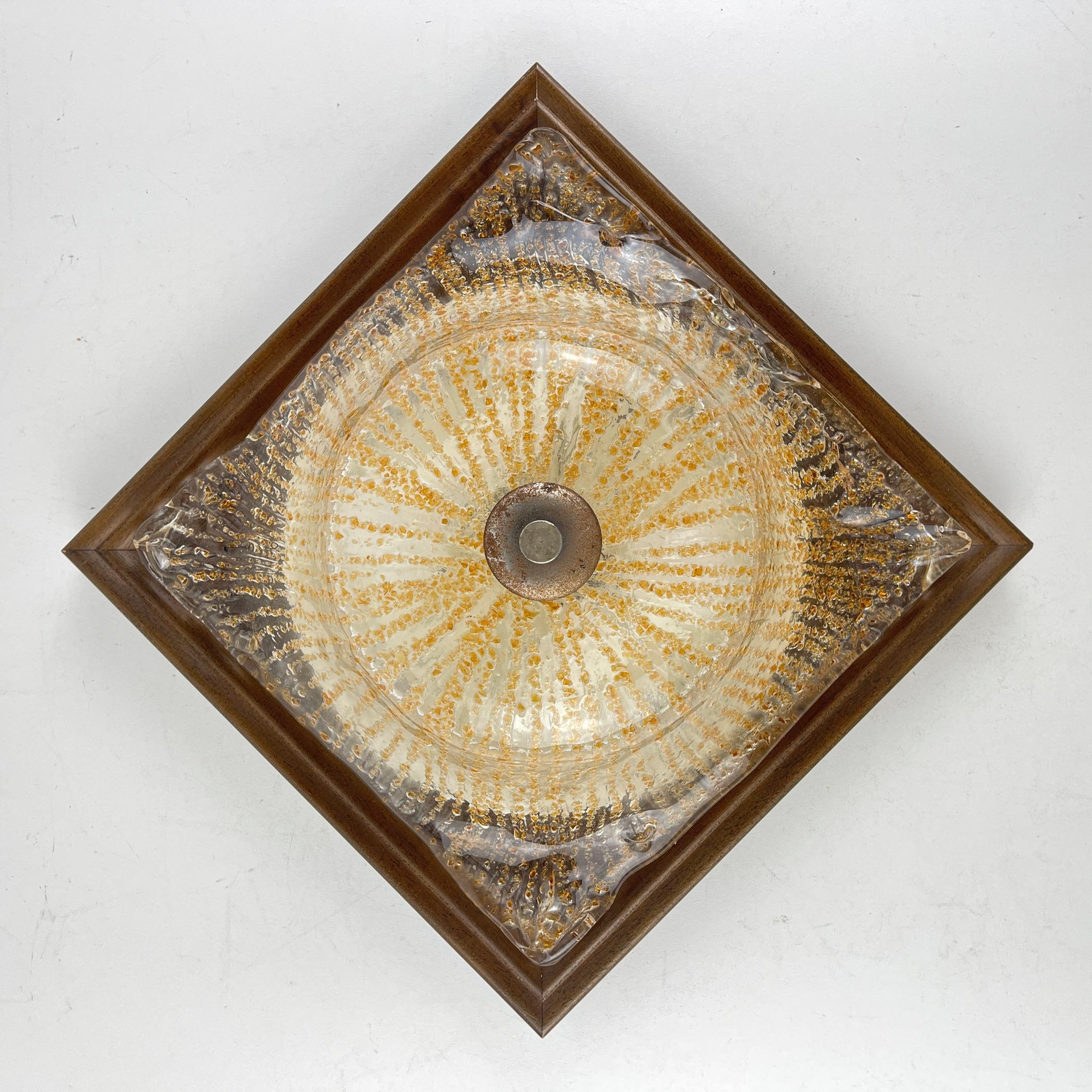 Laissez-vous séduire par l'enchantement du verre de Murano avec cette lampe exquise, fabriquée en Italie dans les années 1970. Son abat-jour à effet de verre glacé, témoin de l'art de Murano, est élégamment apposé sur un socle en bois orné d'une