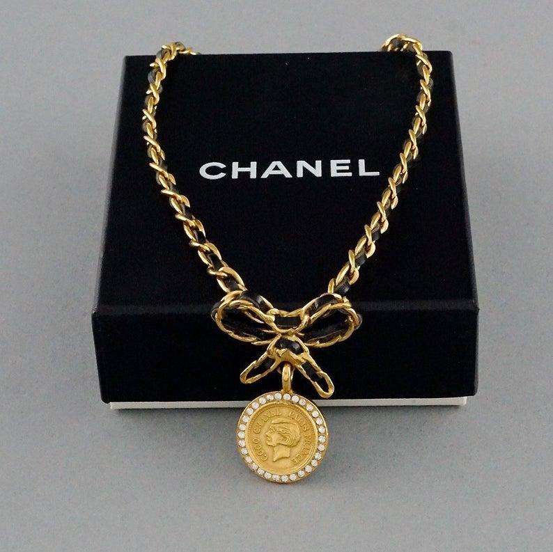 Vintage Iconic CHANEL Coco Medallion Rhinestone Medallion Leather Chain Bow Choker Necklace

Measurements:
Height: 1.96 inches (5 cm)
Wearable Length: 15.43 inches (39.2 cm)

Features:
- 100% Authentic CHANEL.
- Coco Chanel medallion surrounded with