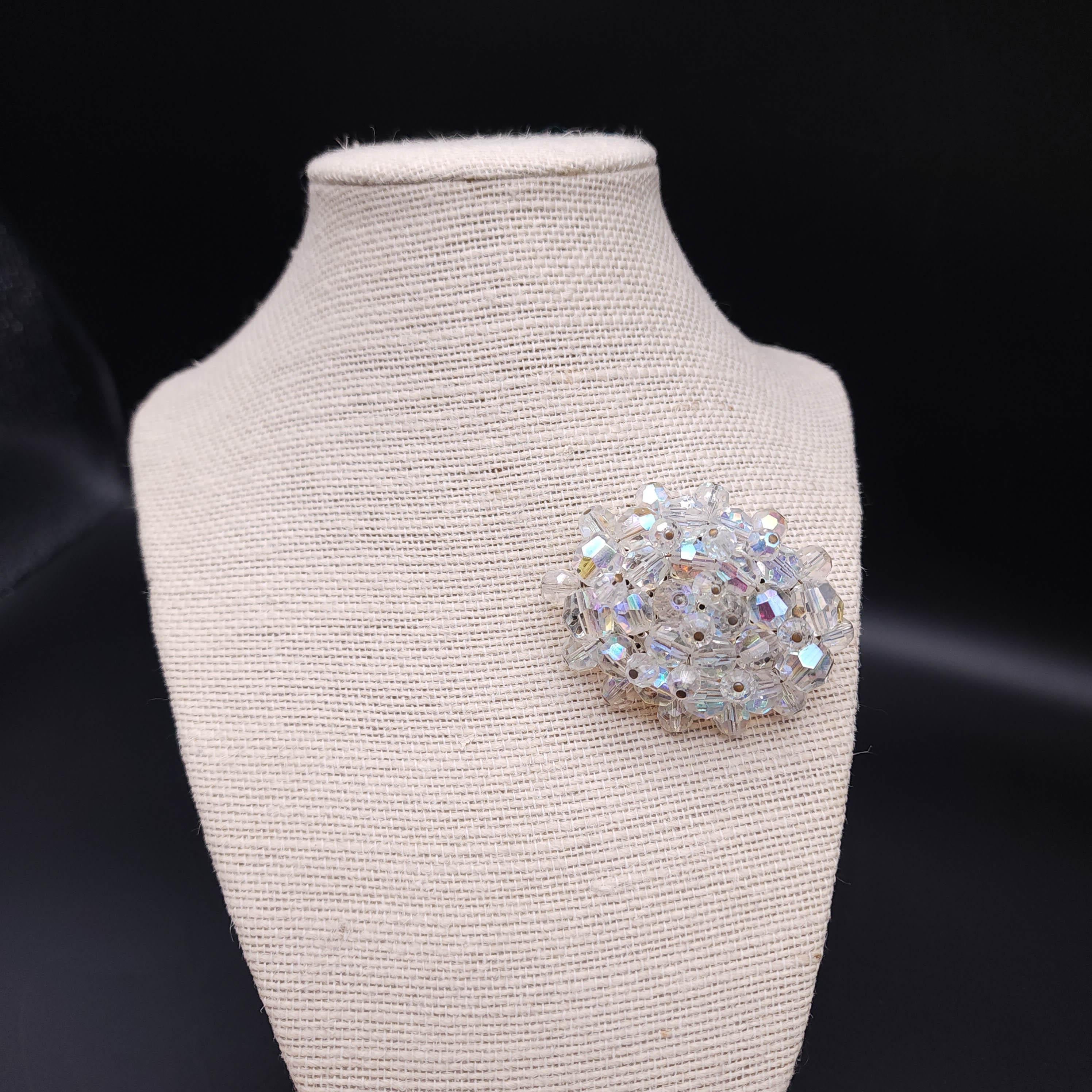 Add a touch of vintage sparkle to your ensemble with this clear aurora borealis crystal cluster oval brooch. This exquisite piece showcases a radiant cluster of Aurora Borealis crystals, known for their mesmerizing play of colors that mimic the