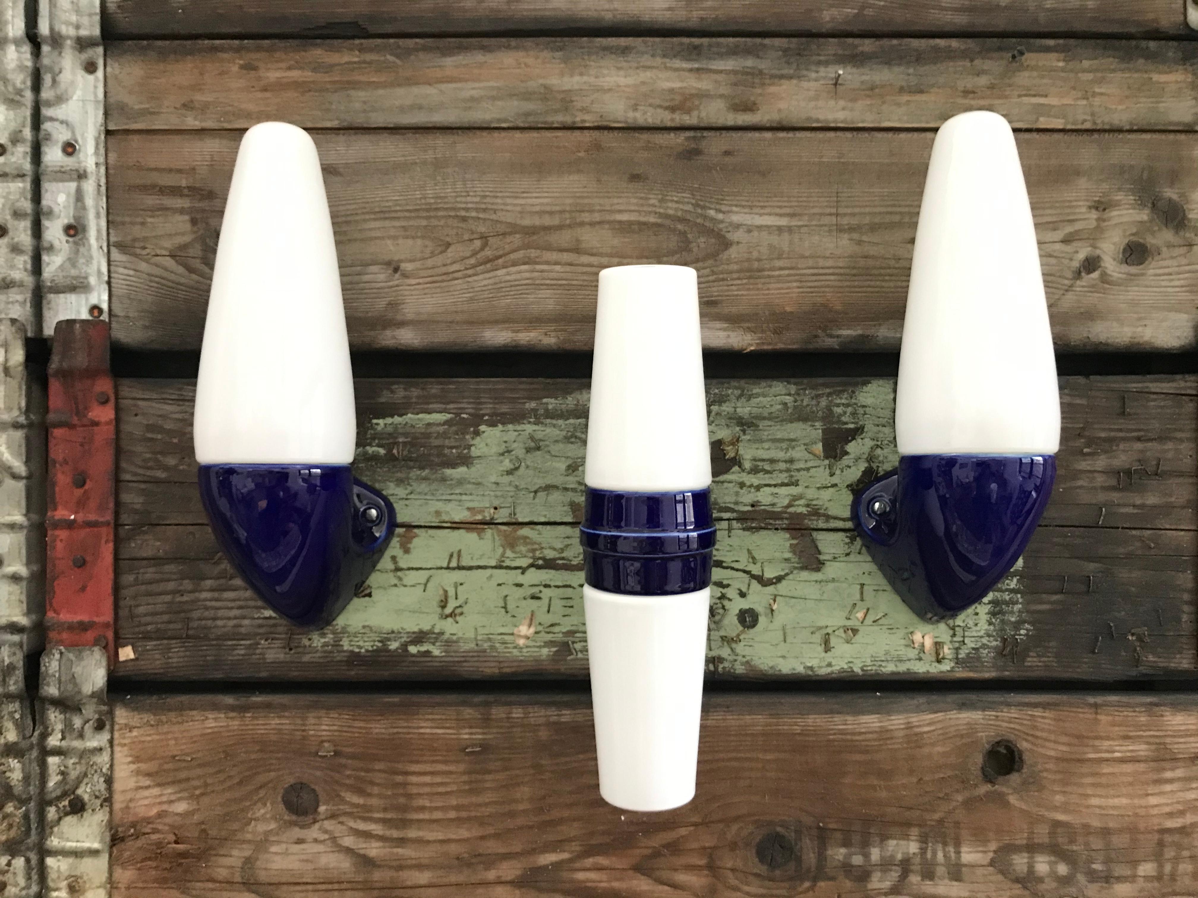 A set 3 vintage Ifö of Sweden ceramic bathroom lamps model 6035 and 6060 from the 1960s in royal blue. 
Designed by Sigvard Bernadotte. 
Opaline glass shades. 
Ceramic bulb holders for an E15 bulb
Lamps can be used as up or down lights.
A set