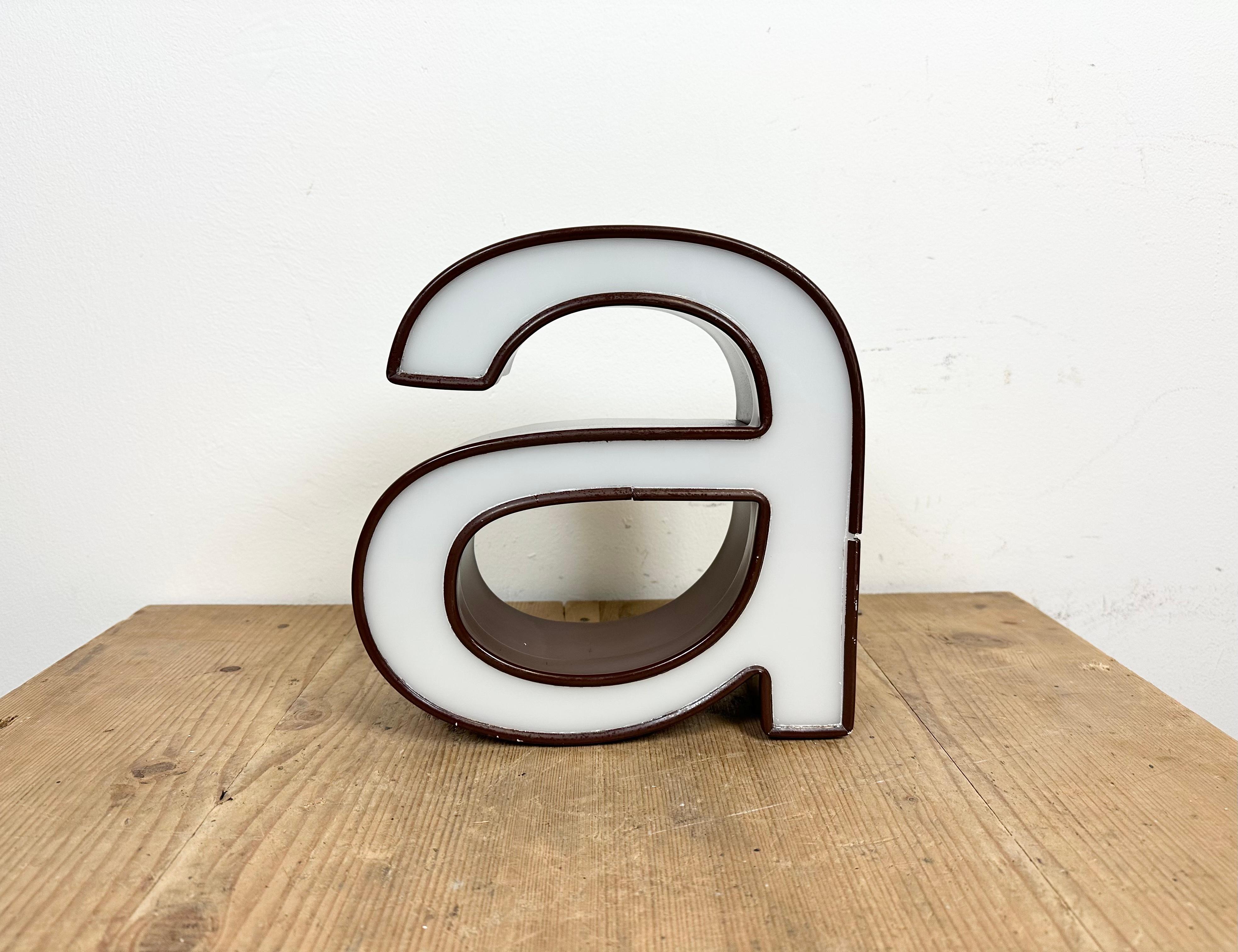 This vintage industrial illuminated letter A was made in Italy during the 1970s and comes from an old advertising banner. It features a brown metal body and a white plexiglass cover. It is equipped with a LED strip. The letter can be used as a table