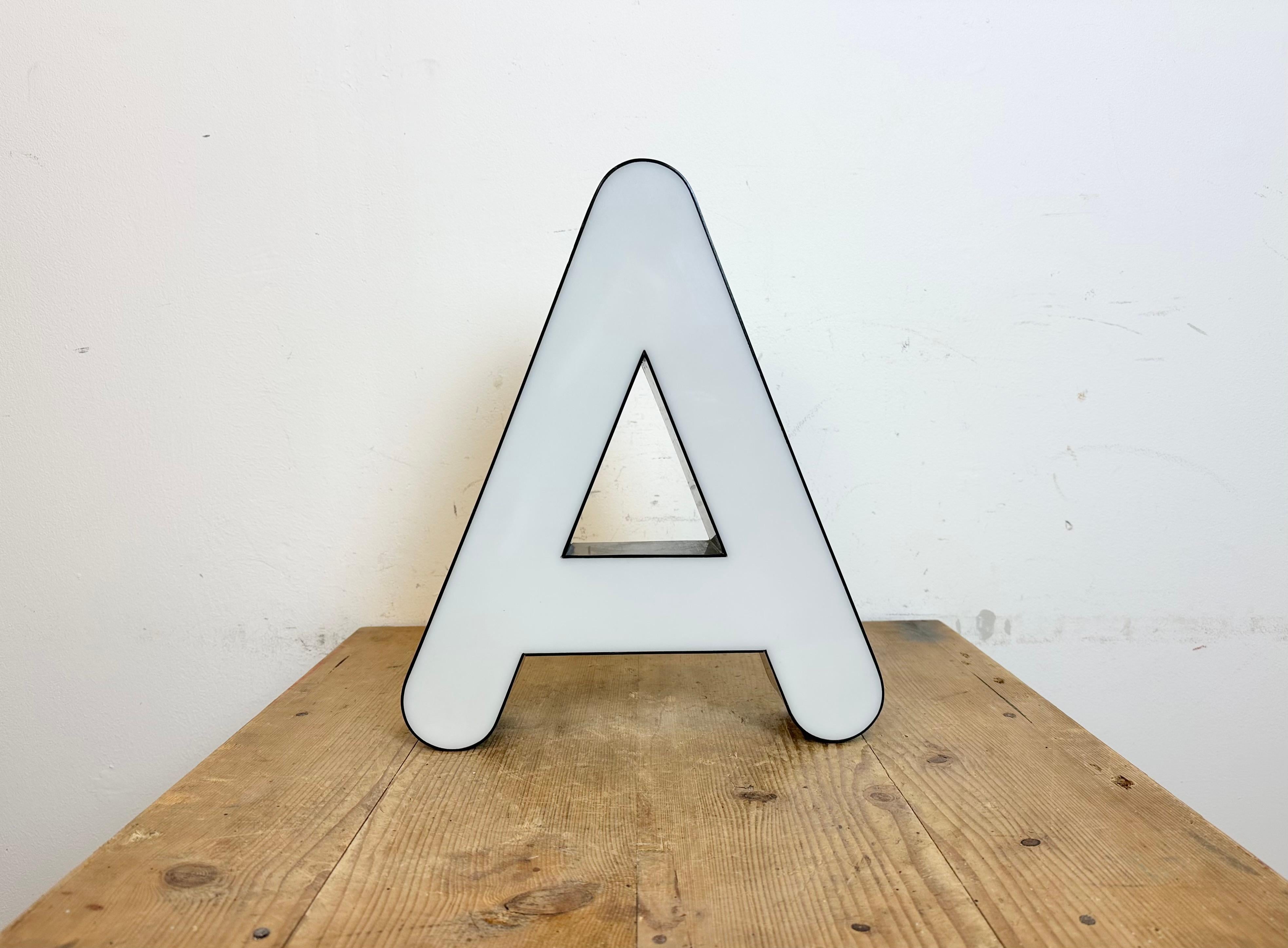 This vintage industrial illuminated facade letter A was made in Italy during the 1970s and comes from an old advertising banner. It features a black bakelite body and a white plexiglass cover. It is equipped with a LED strip. The letter can be used