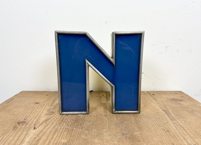 This vintage industrial illuminated letter N was made in Italy during the 1970s and comes from an old advertising banner. It features a yellow metal body and a blue plexiglass cover. It is equipped with a LED strip. The letter can be used as a table