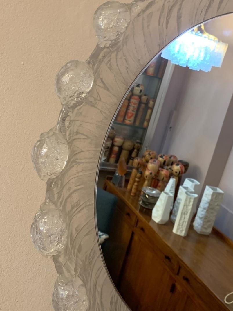 A 1970s German back-lit wall mirror formed from a lucite mottled frame in the shape of a water droplet. Manufactured by Miradur-Werk, Dusseldorf. The manufacturer's label is still visible on the frame. The round mirror hooks onto a white wooden