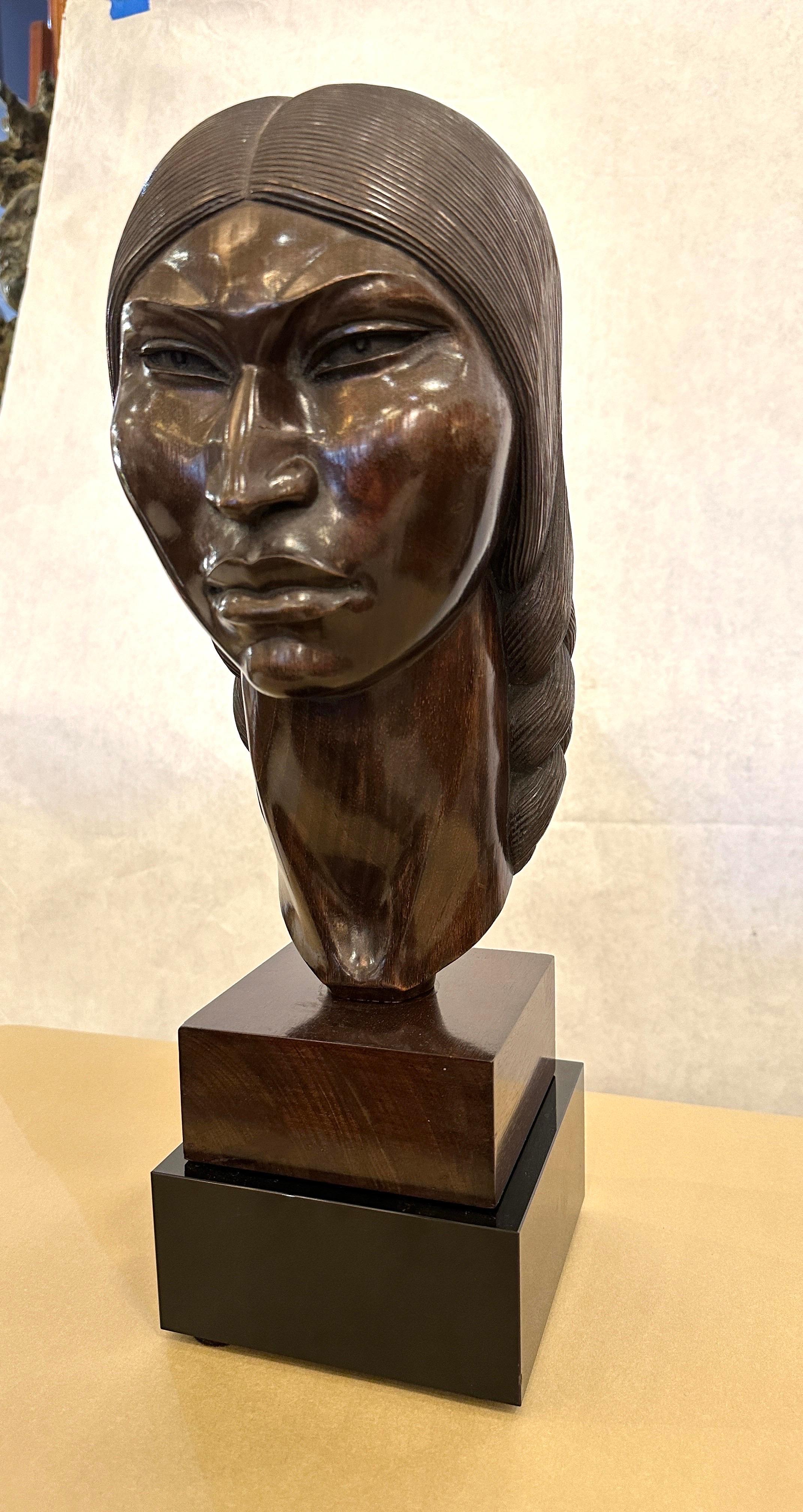 This beautifully and intricately carved vintage bust of an Incan warrior female by SARAVIA. This wonderful dark wood sits atop a custom created black glass pedestal base (not attached). The features of the face and hair are masterfully executed.