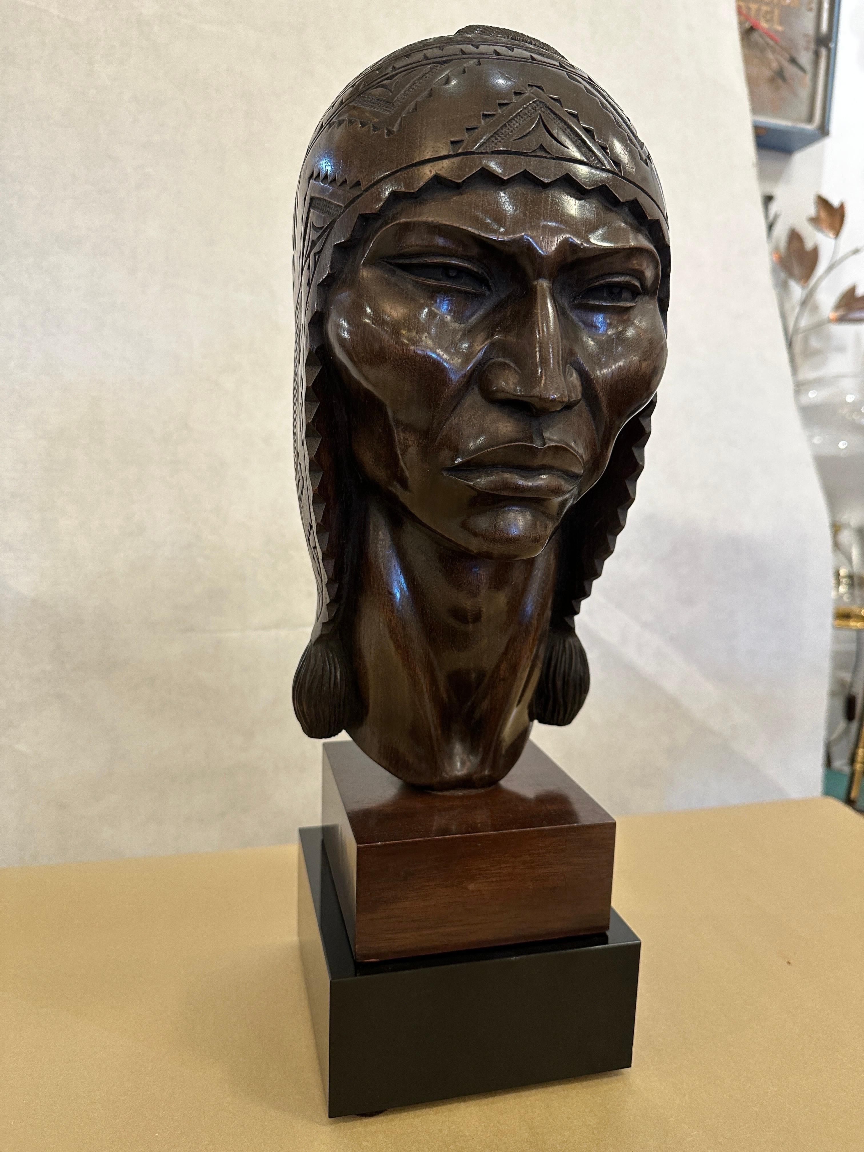 This beautifully and intricately carved vintage bust of an Incan warrior male by SARAVIA. This wonderful dark wood sits atop a custom created black glass pedestal base (not attached). The features of the face, hair and woven cap are masterfully