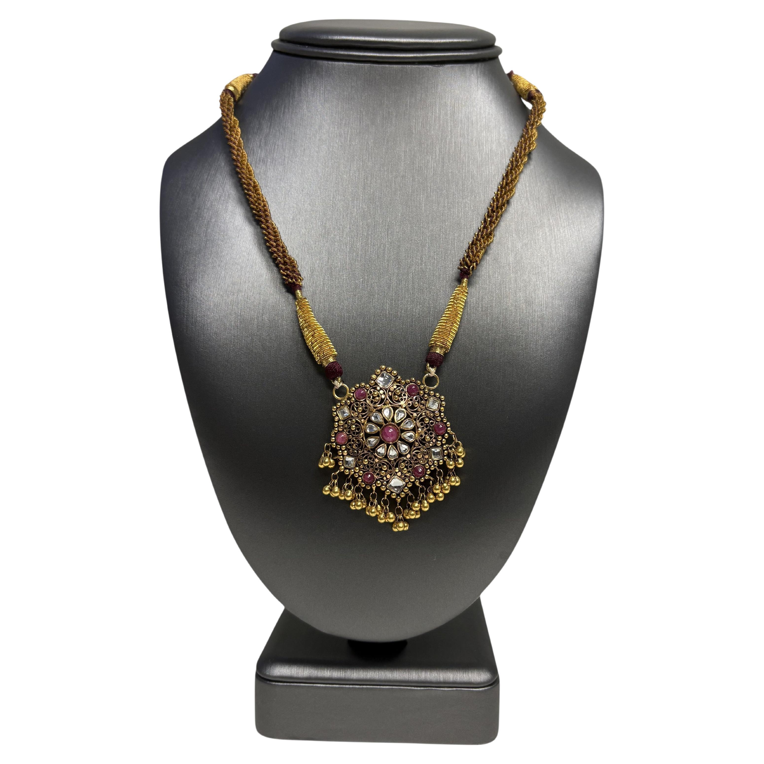 Questo straordinario ciondolo indiano vintage in oro giallo 22k con pietra su una collana di nappe viola è in ottime condizioni e pronto per essere spedito!

Un pezzo unico e audace, questa collana presenta un grande ciondolo in oro giallo 22k