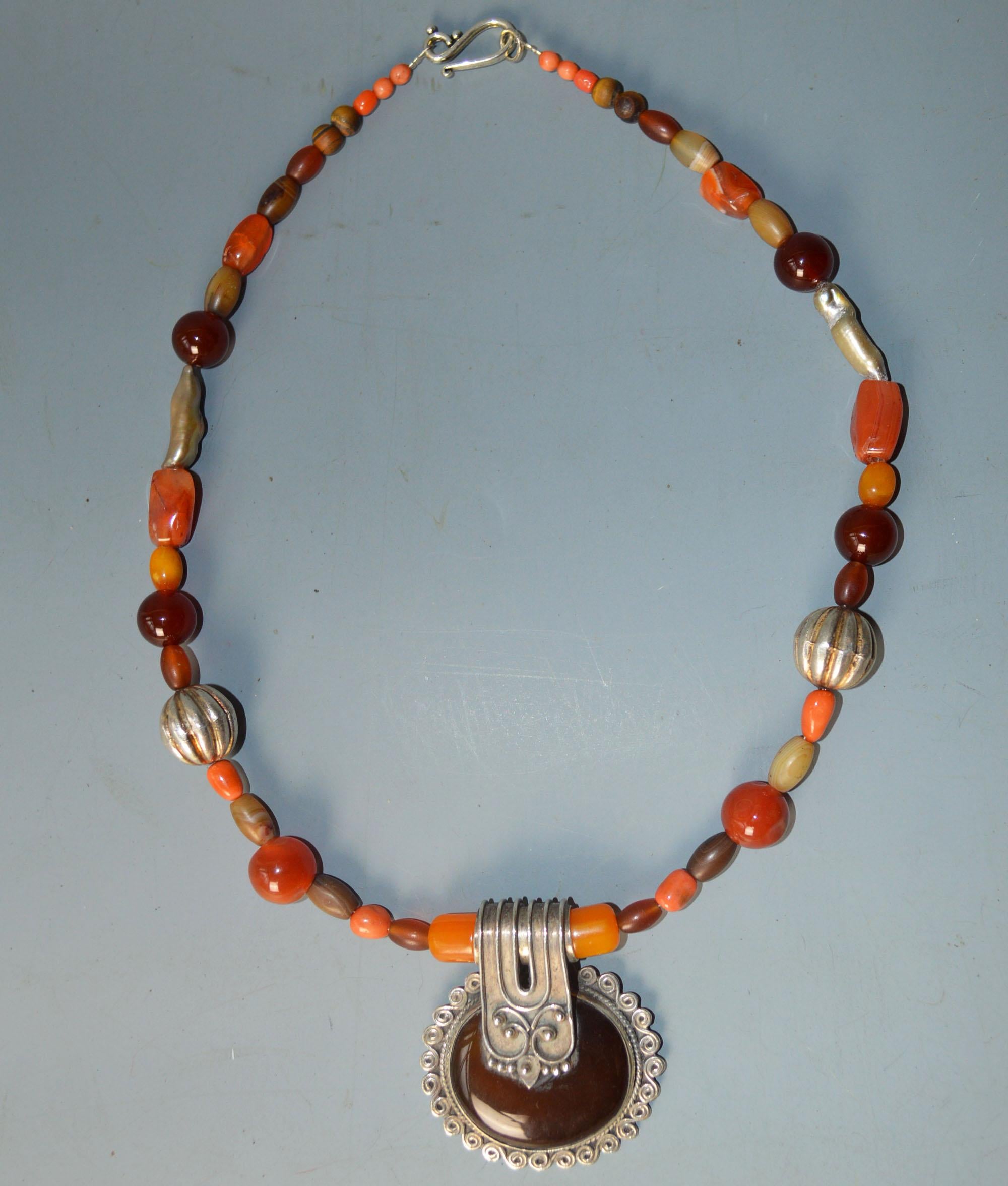 A fine Vintage Asian/  indian silver coral and gemstone necklace 

Central pendant in hand crafted silver with agate with real natural red coral beads silver beads natural pearl and gemstones.
period 1970`s

 
