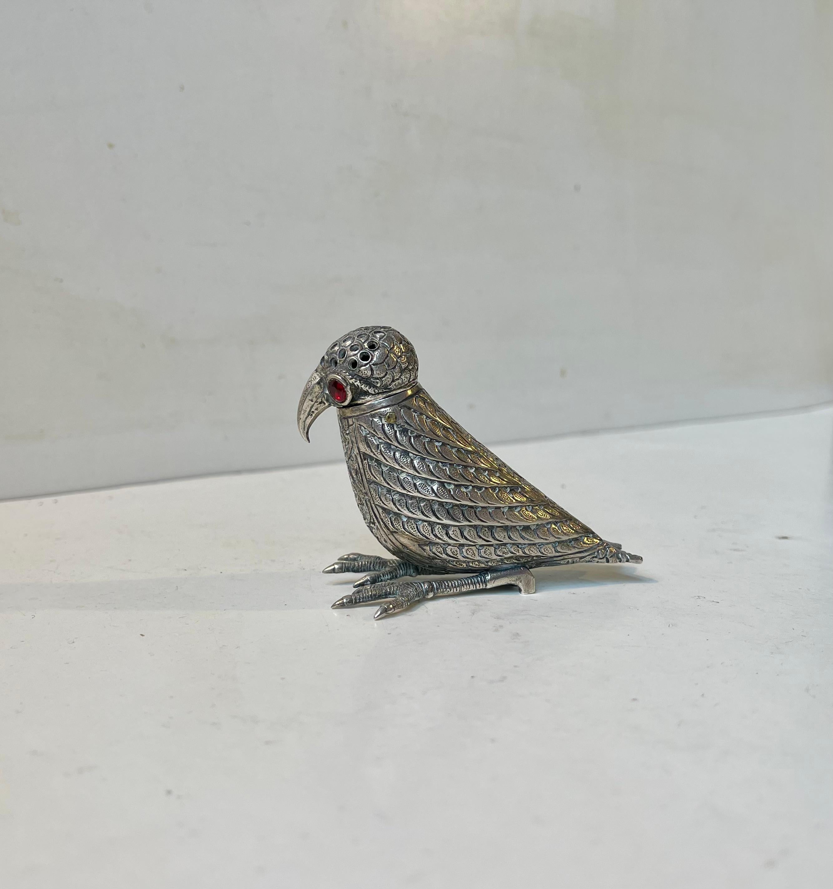 Adorable bird sugar or pepper dispenser in hand-cut silver. A standing small hawk-like bird, with curved beak, folded in wings and round-cut garnet gem eyes. It has removable head with a simple push-turn-fit. The decoration is of typical Kashmiri