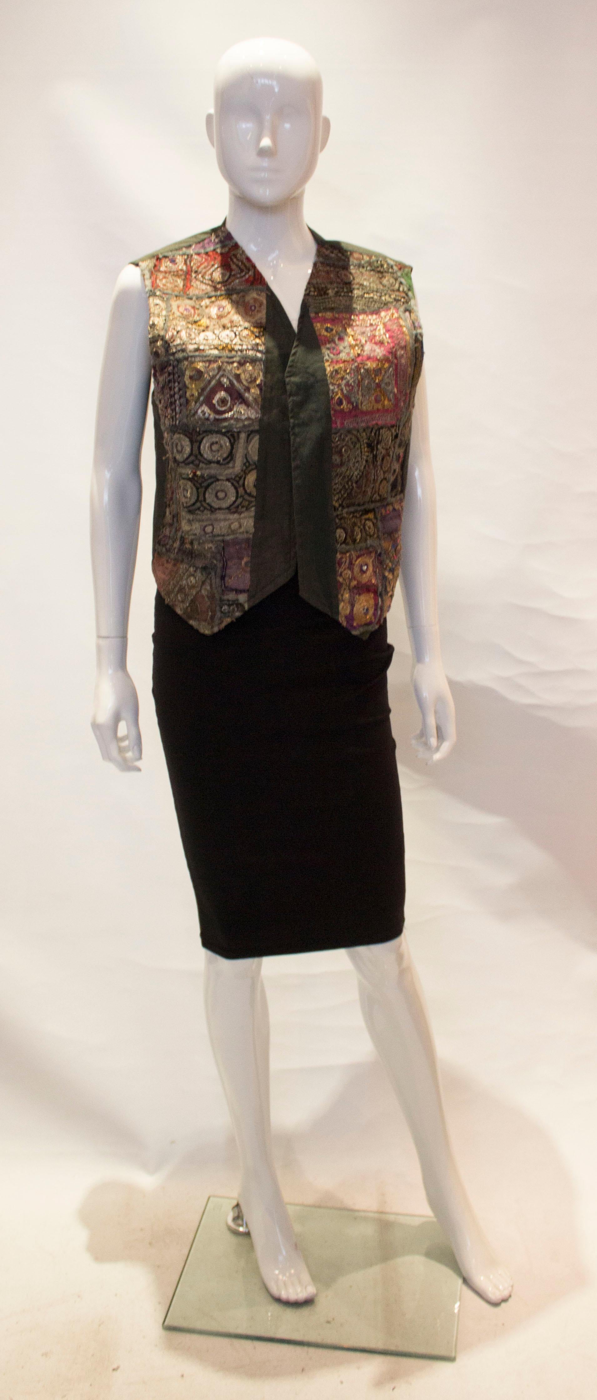 A fun and east to wear vintage Indian waistcoat. The fabric is a grey cotton with decoration on the front.