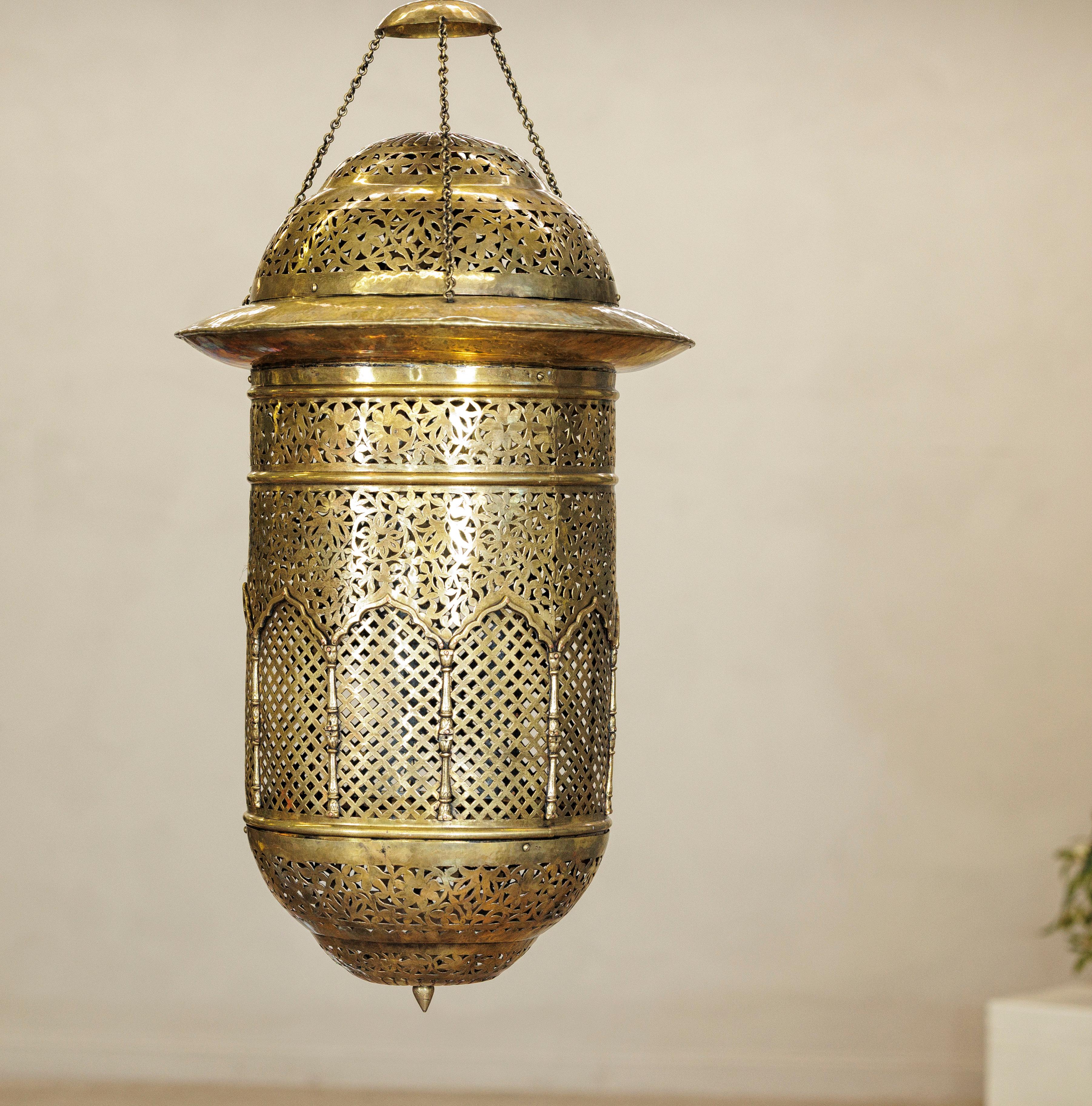 This vintage Indian hanging lantern is crafted from solid brass with intricate hand-pierced decoration. Its tall cylindrical body (measuring 31