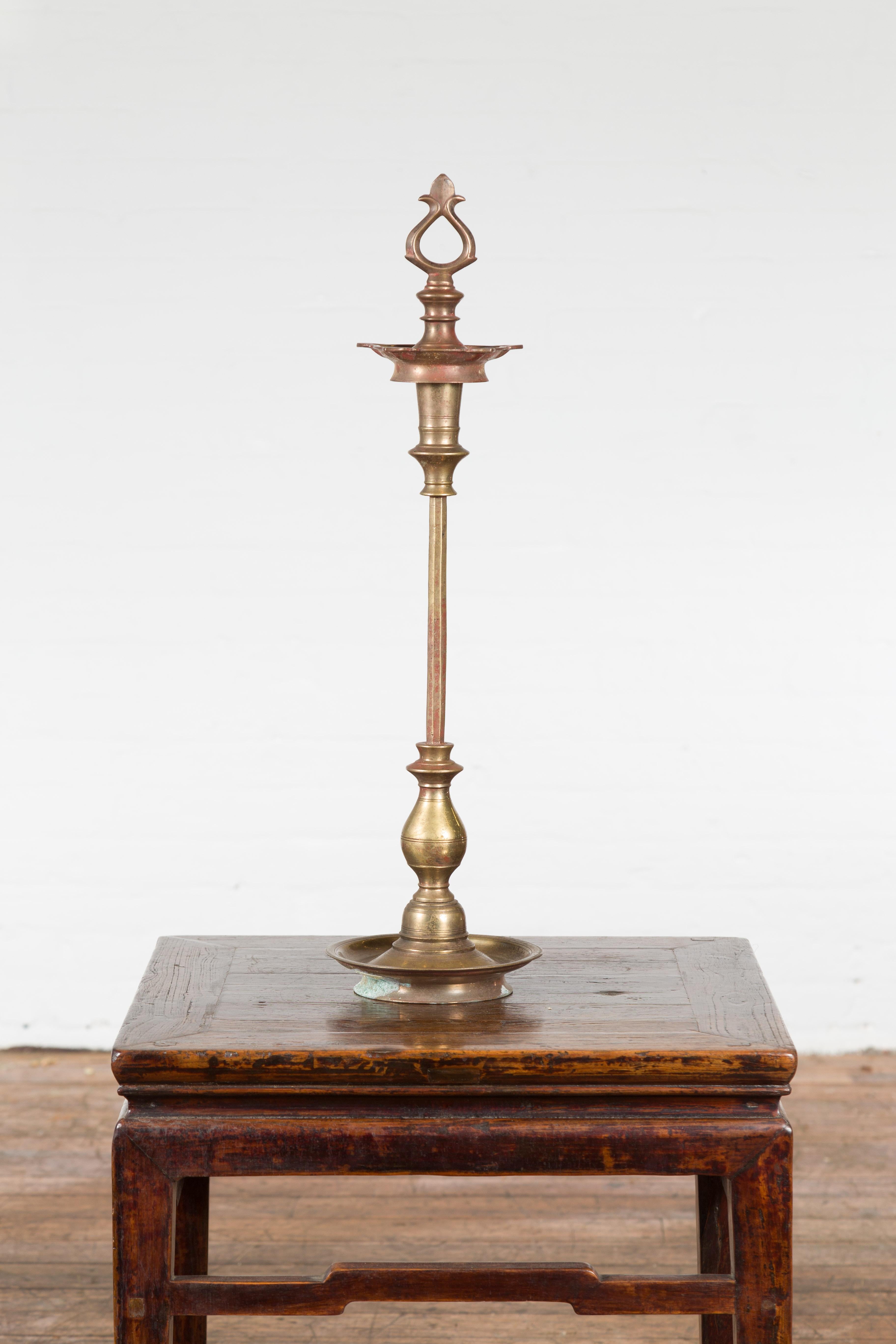 An elegantly defined brass vintage pricket from India used to host candles. The pricket is centered on a slightly raised circular base with the edges slightly raised while the top where the candle will sit is beautifully crafted with defined curves