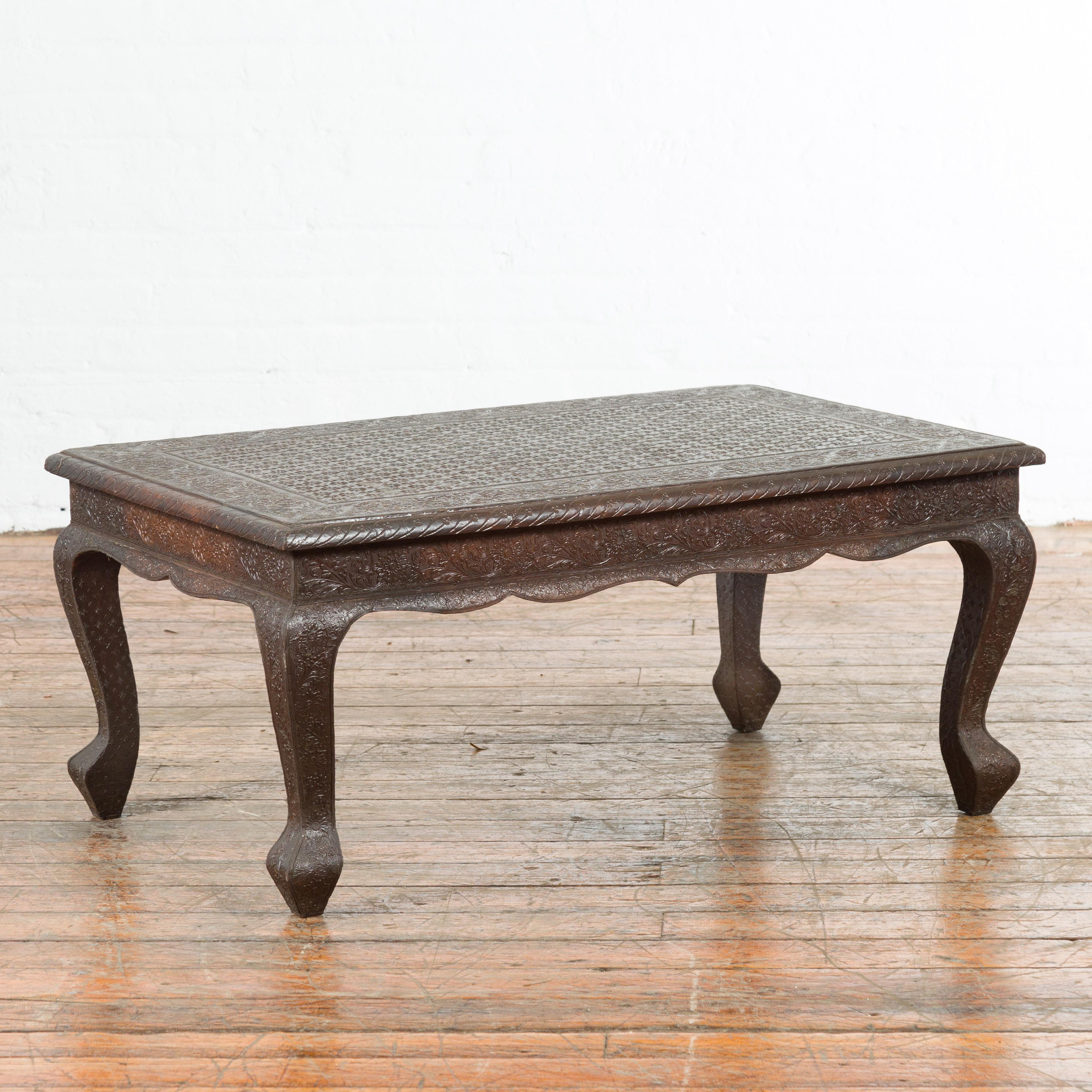 An Indian vintage metal coffee table from the mid 20th century, with embossed design created with metal dyes, floral motifs and cabriole legs. Created in India during the midcentury period, this coffee table features a rectangular top adorned with