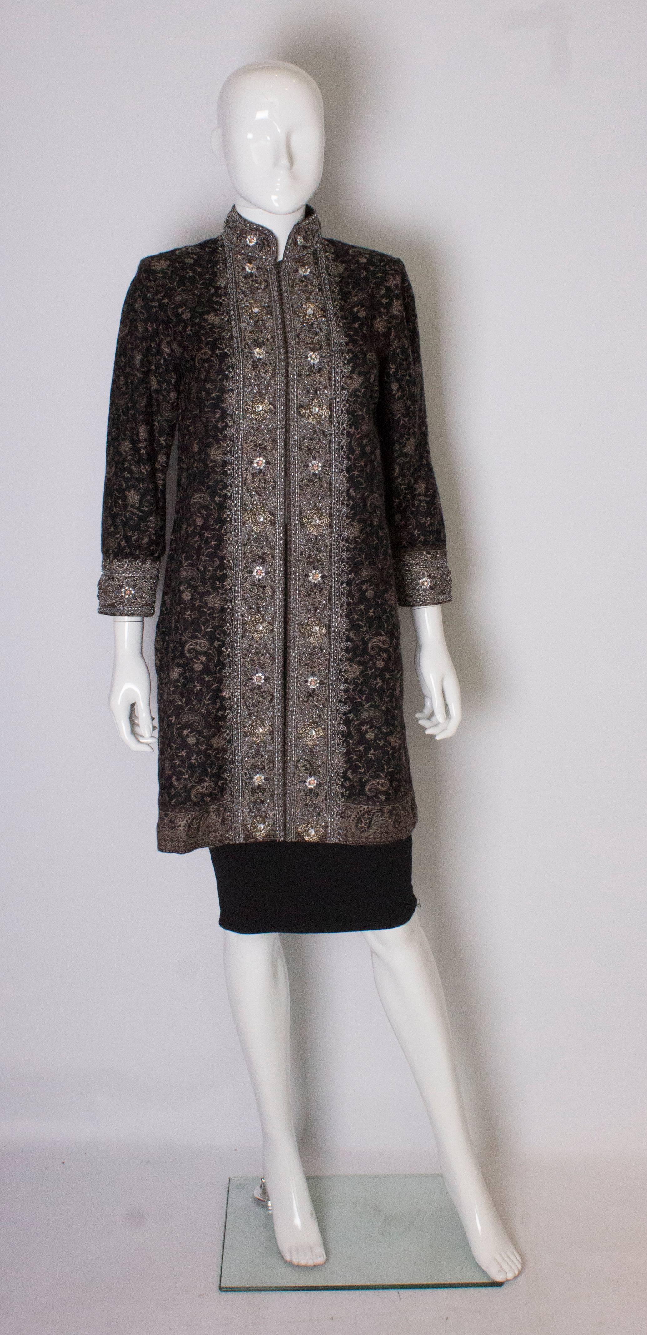 A chic  embroidered evening jacket. This jacket is in a black wool/kahsmir mix with a beige floral design. It has  embroidery detail on the collar and cuffs, with 12'' slits on each side.