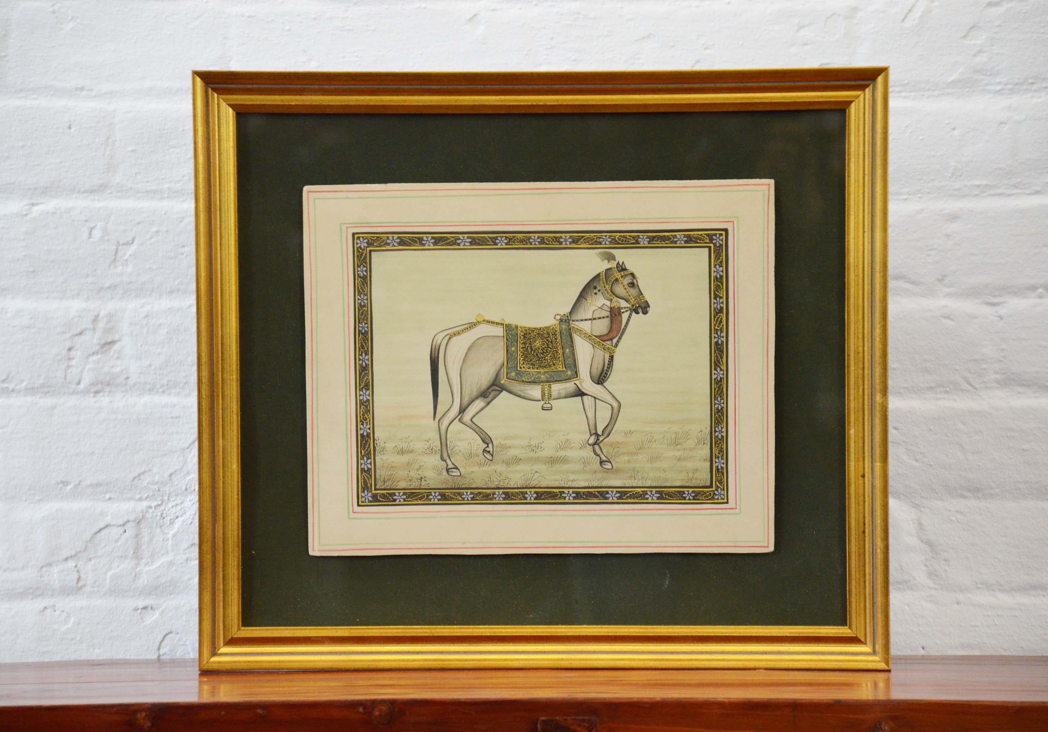 A vintage Indian hand-painted Mogul style horse from the mid 20th century, with gilded wooden frame. Created in India during the midcentury period, this painting on silk paper depicts a Mogul horse graciously standing sideways while delicately