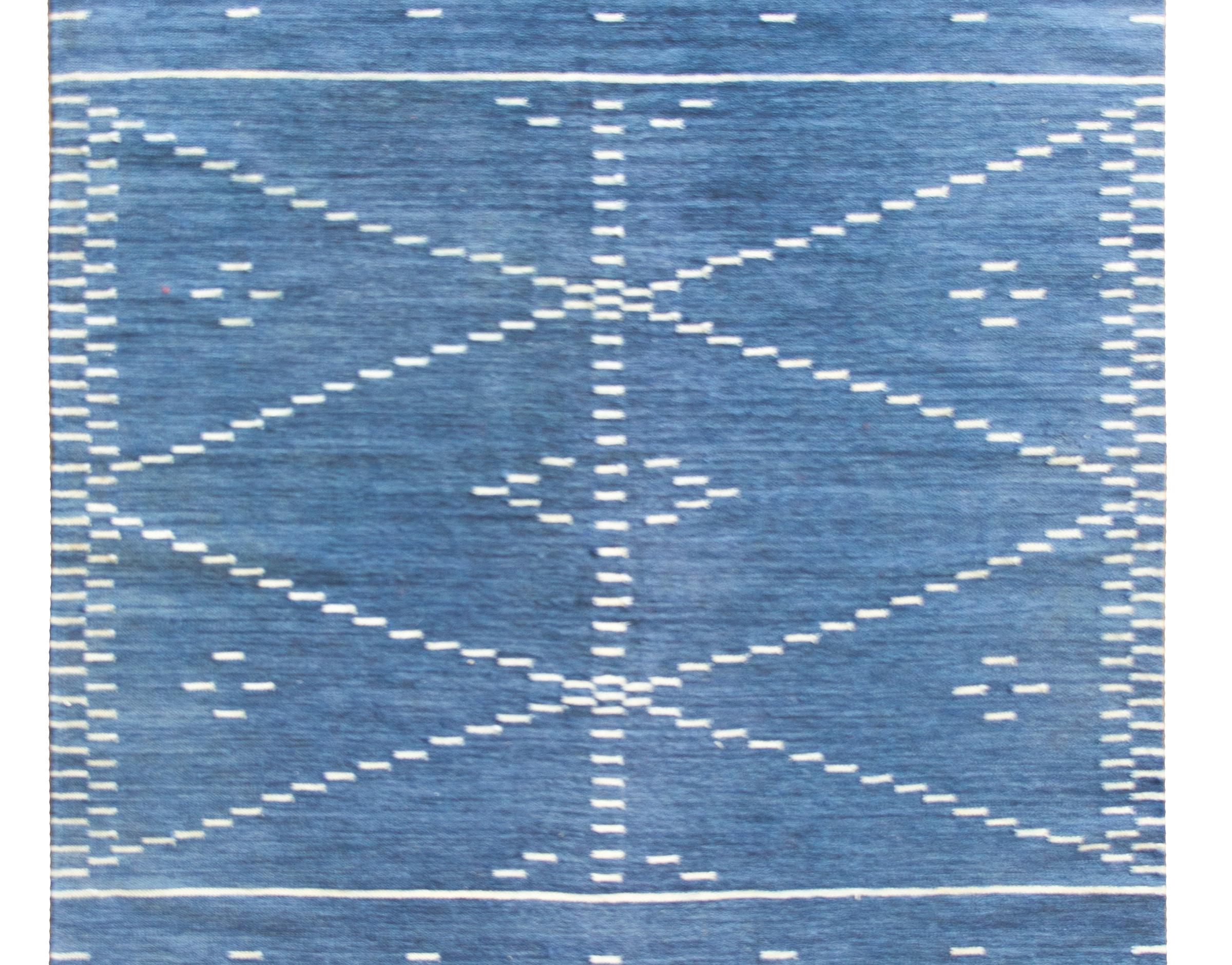 A wonderful late 20th century Indian hand-woven kilim rug with an indigo ground covered in white diagonal stripes in the center with horizontal stripes at each end.  