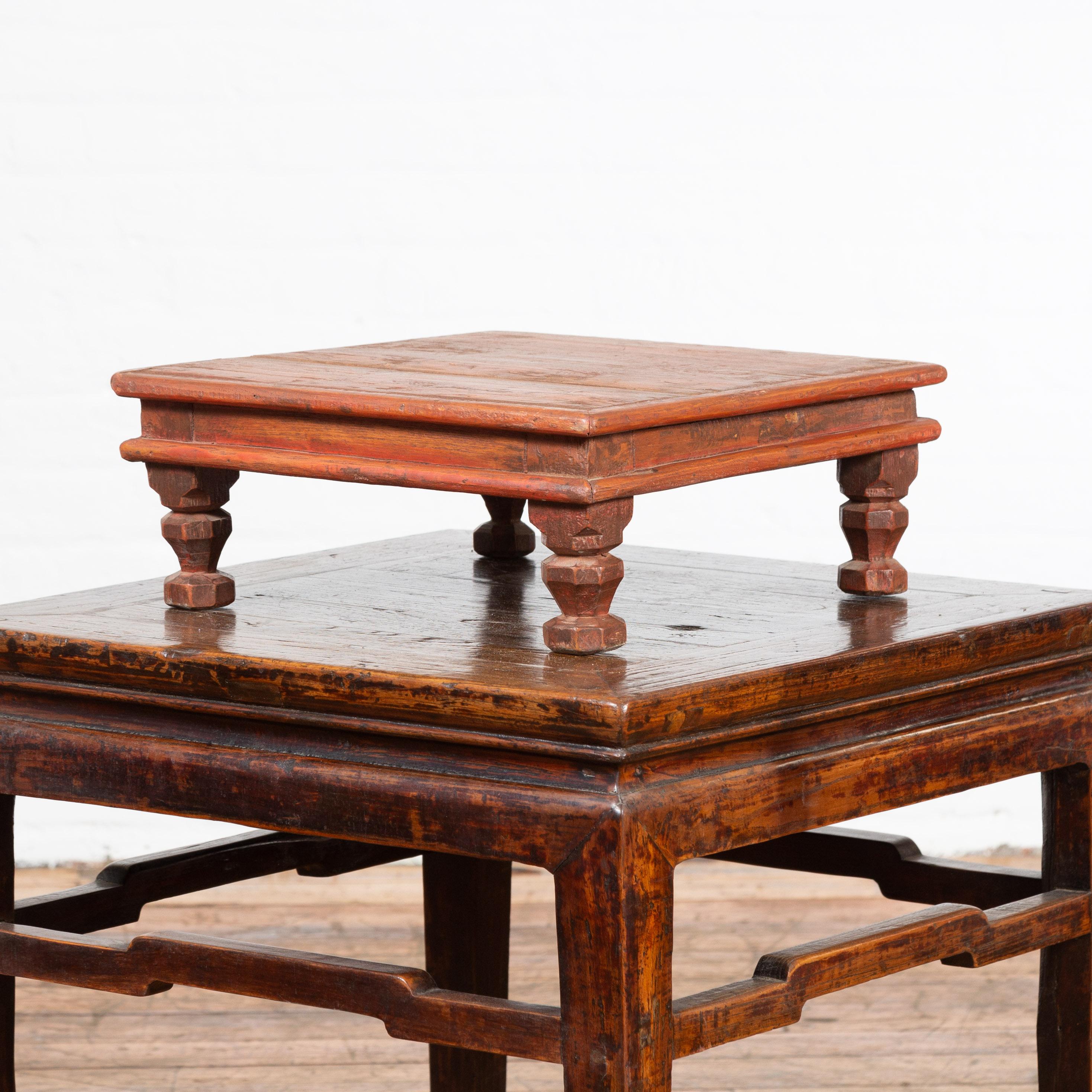 An Indian vintage low wooden prayer table from the mid 20th century, with carved legs. Created in India during the midcentury period, this vintage wooden prayer table features a square planked top sitting above a recessed apron. Four small carved
