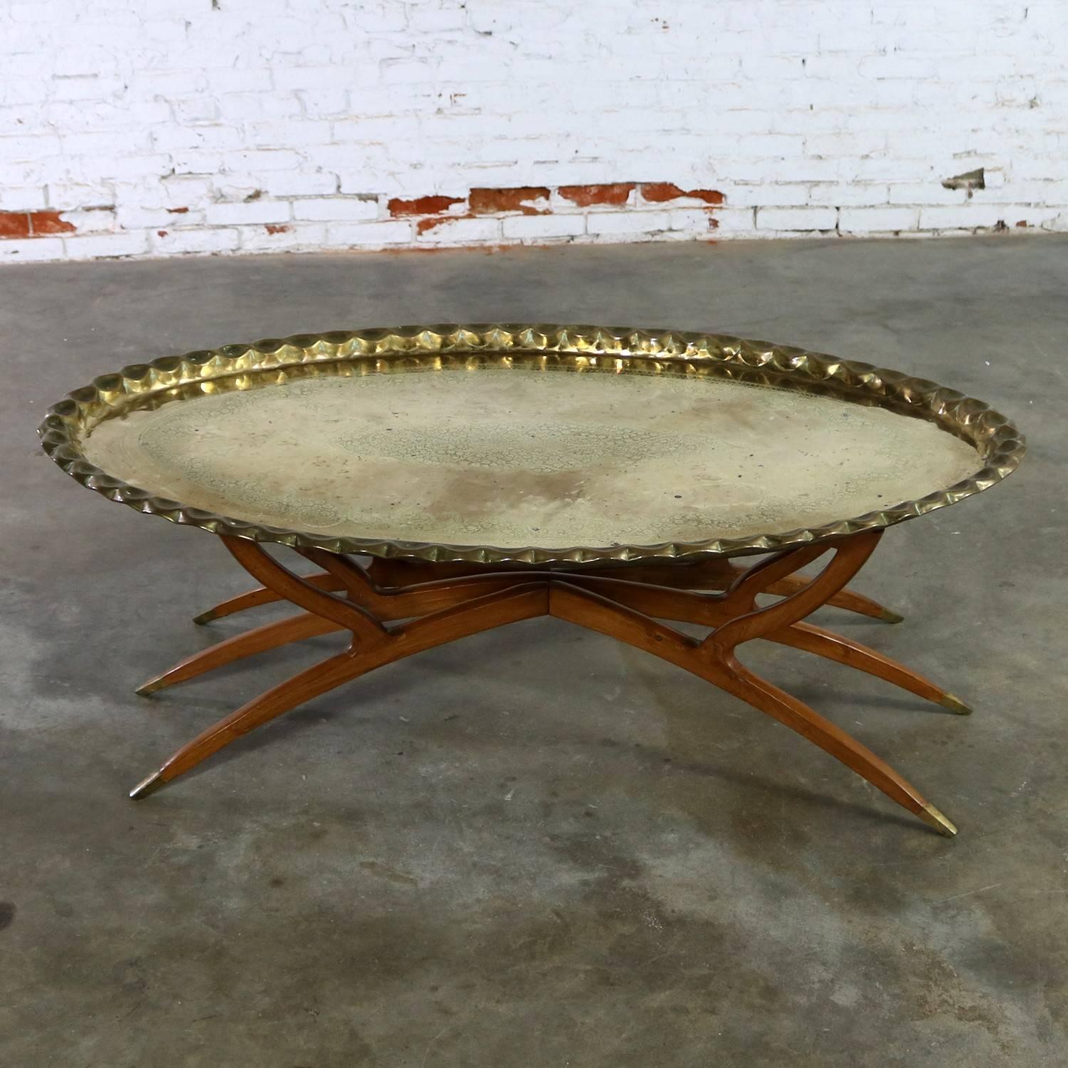 Handsome vintage Moroccan style oval brass tray coffee table on spider legs made in India. This rather campaign style coffee table is in fabulous vintage condition with a gorgeous patina, including scratches and spotting, that only comes with age