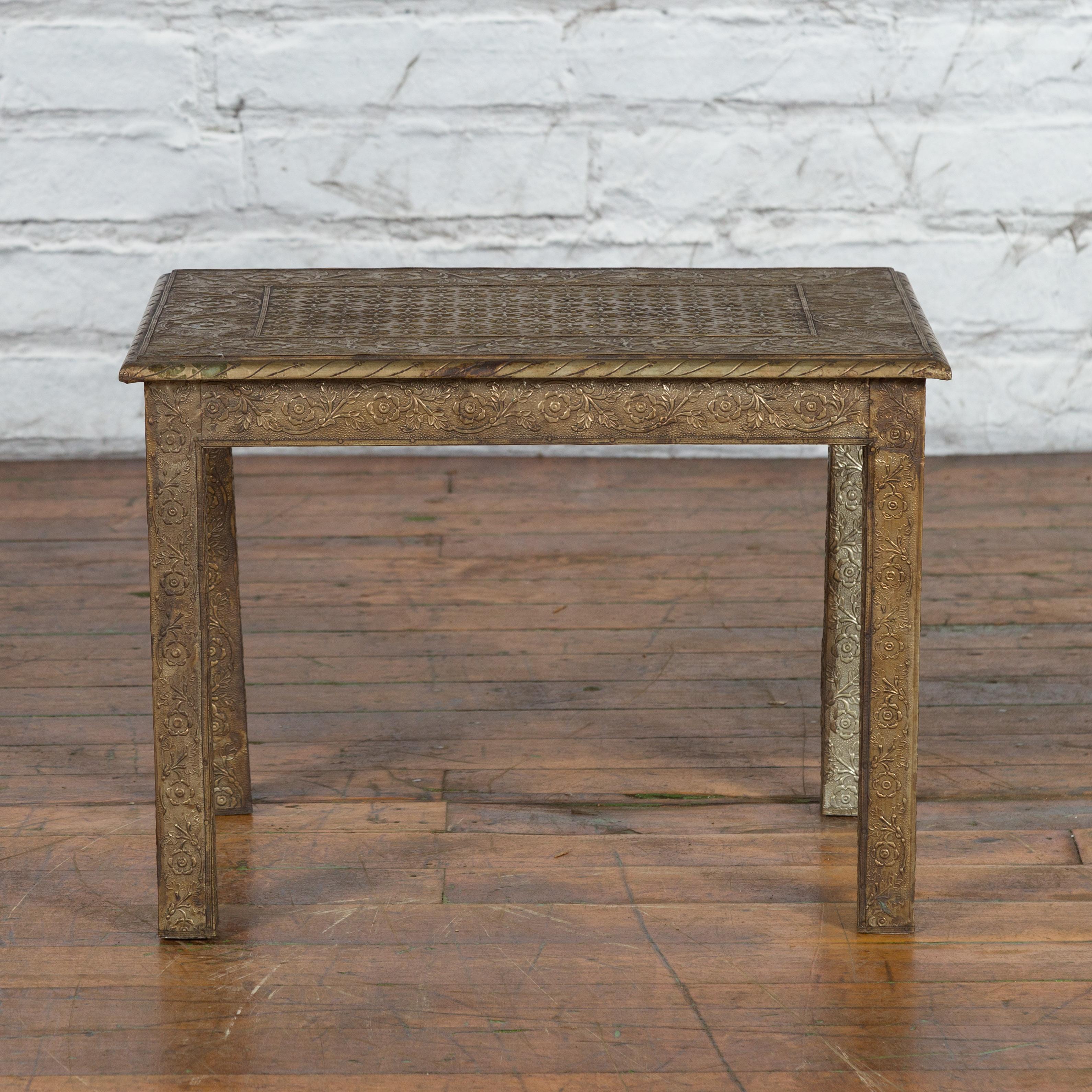 A vintage Indian low side table from the mid 20th century with repoussé floral motifs, nickel and silver finish, straight legs and distressed patina. Created in India during the midcentury period, this low drinks table features a rectangular top