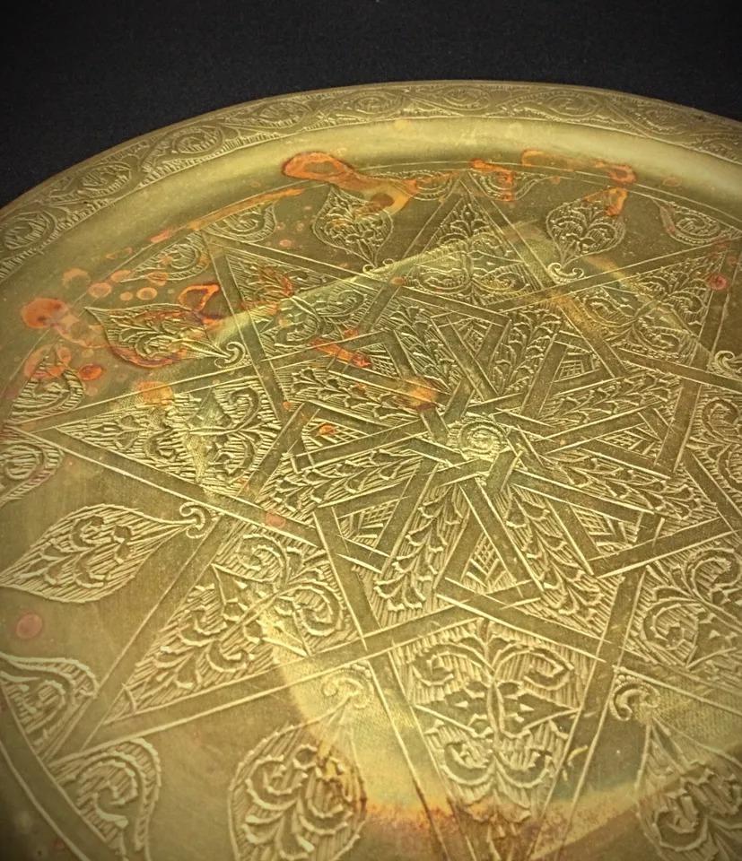 This vintage brass tray, featuring an intricate Swastika motif, reflects traditional Indian or Oriental design. The tray is in good overall condition but shows signs of light oxidation and small scratches on both the top and bottom, typical for its