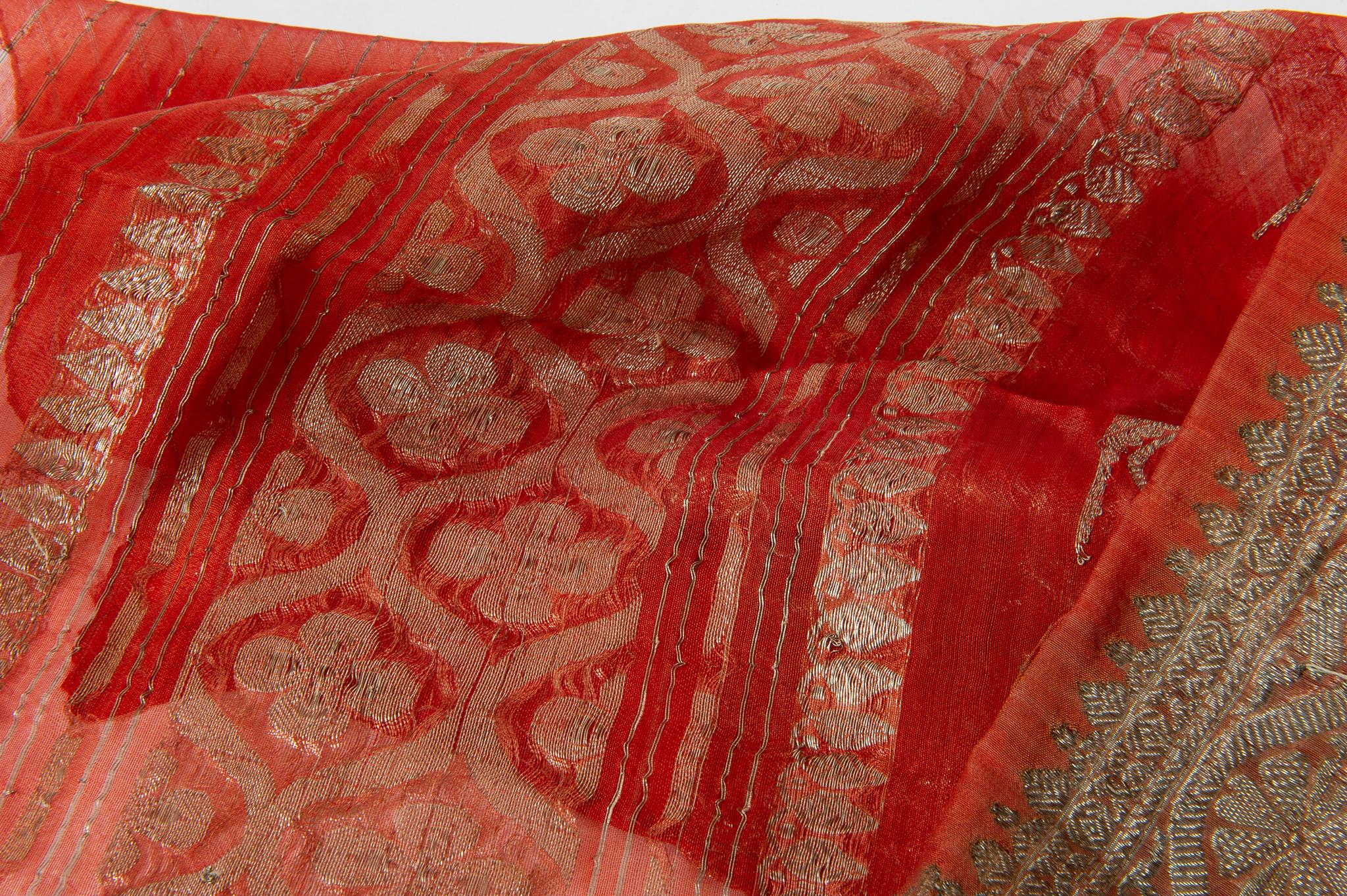 Sari indien vintage dans une belle couleur corail, avec des motifs floraux et une riche bordure. Il a été porté, ce qui explique la présence de quelques taches, même si elles ont été lavées.
Certains saris sont en soie, d'autres en mélange