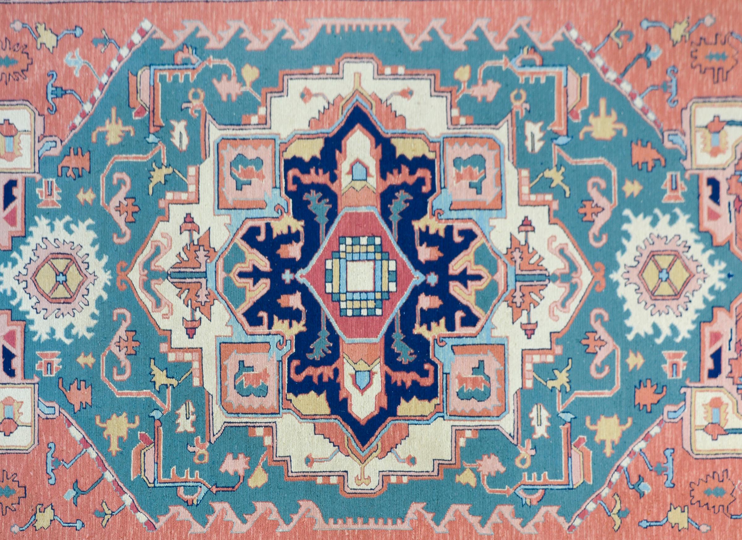 A beautiful late 20th century Indian flatweave rug woven with a Serapi pattern containing myriad large stylized floral patterns woven in pale pinks, yellows, blues and greens, and surrounded by a complimentary floral patterned border.