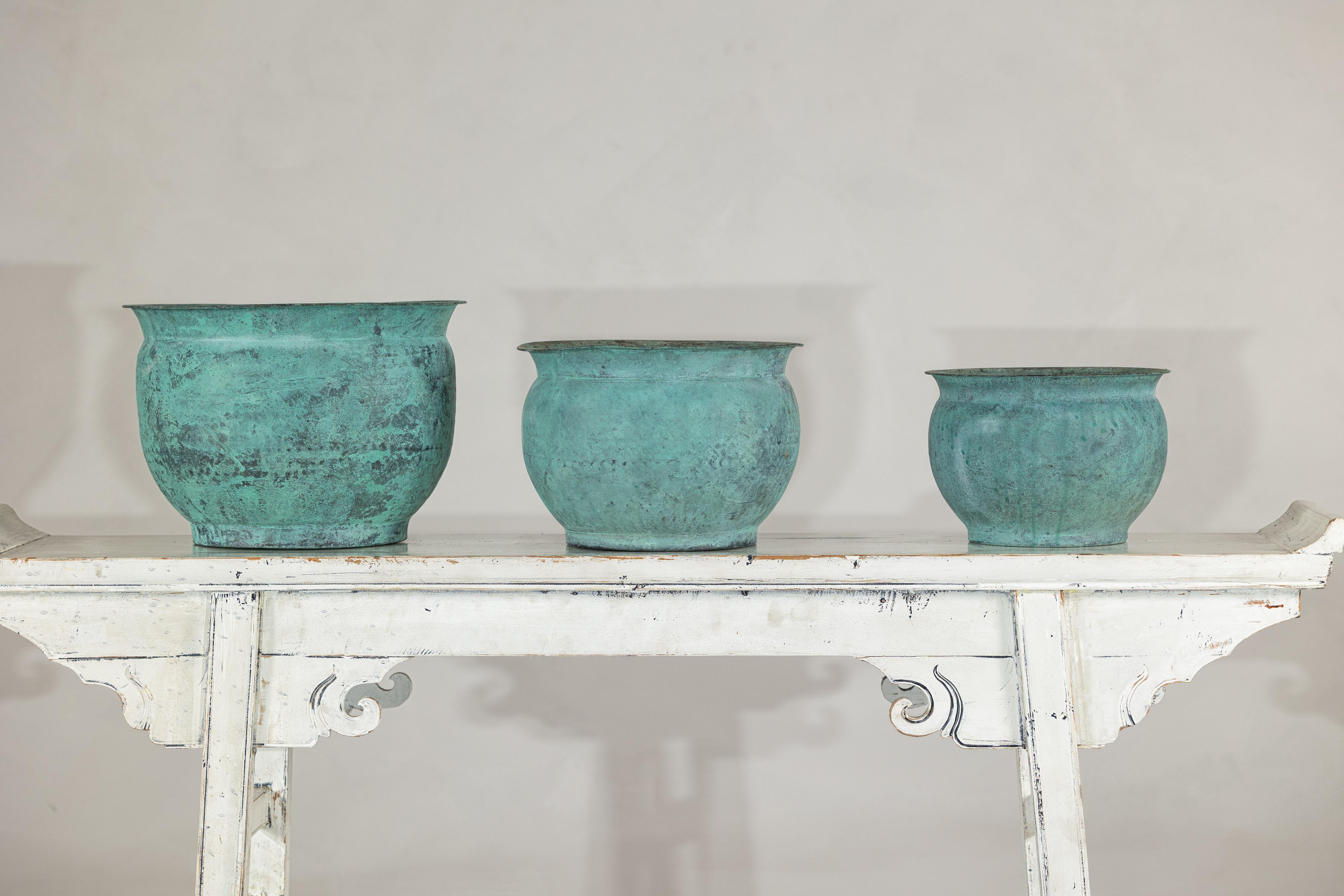 Questo affascinante set di tre cache pot in rame vintage, realizzati a mano in India, conferisce un'eleganza calda e consumata a qualsiasi ambiente interno o giardino. Ogni vaso presenta un bordo delicatamente svasato, un corpo arrotondato e una