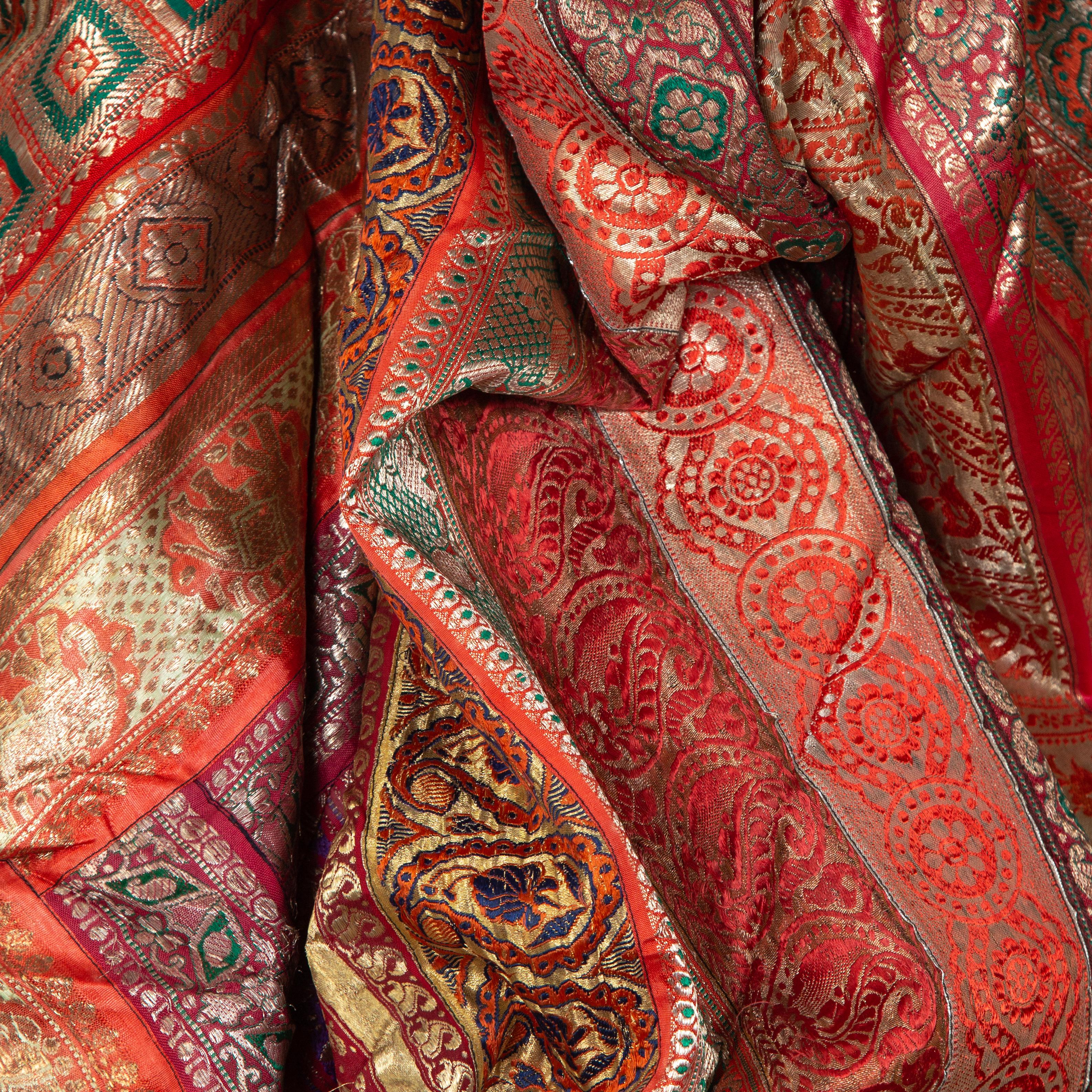Un grand tissu indien vintage en soie brodée de la seconde moitié du 20e siècle avec des tons rouges, orange, violets, verts et dorés entre autres. Probablement originaire du Rajasthan, ce superbe tissu en soie est constitué de pièces de sari