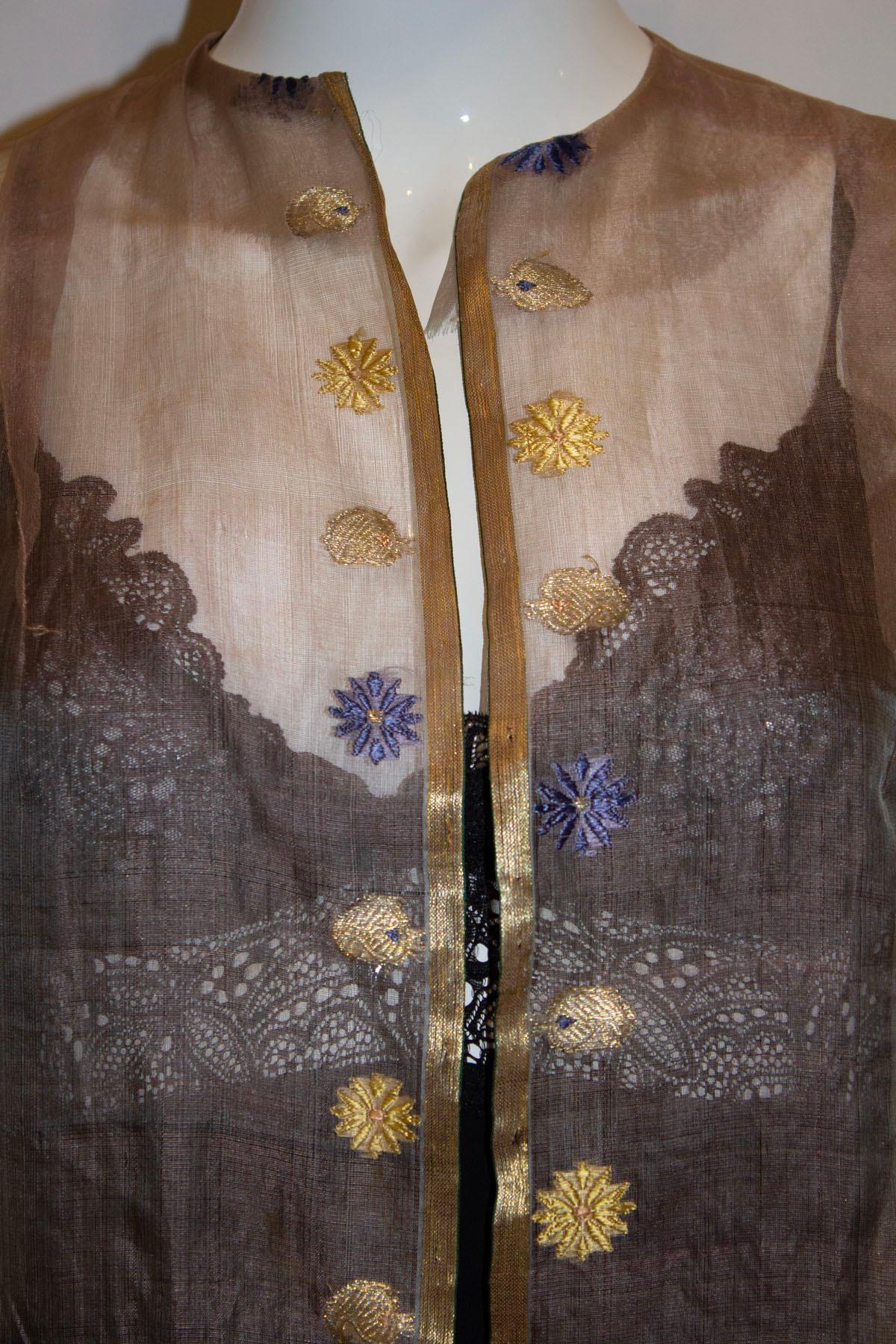 Ein furchtbar hübscher Vintage-Seiden-Organza-Staubmantel. Der Mantel ist in einem hübschen blassrosa Farbton gehalten, mit Goldfaden-Details und Stickereien. Es ist kragenlos, hat ellenbogenlange Ärmel und ist ungefüttert.
Maße: Oberweite bis zu