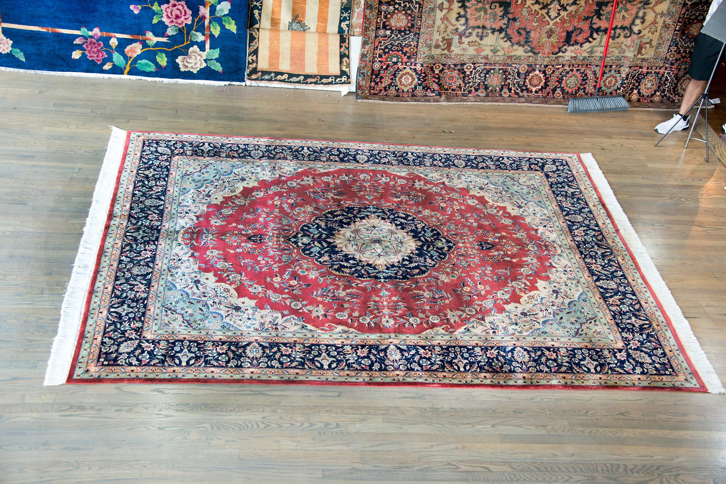 A wonderful late 20th century Indian Tabriz-style rug with a large central complex medallion woven with myriad stylized flowers and leaves, and woven in crimson, indigo, cream, gold, and green.  The border is complex with multiple wide and thin