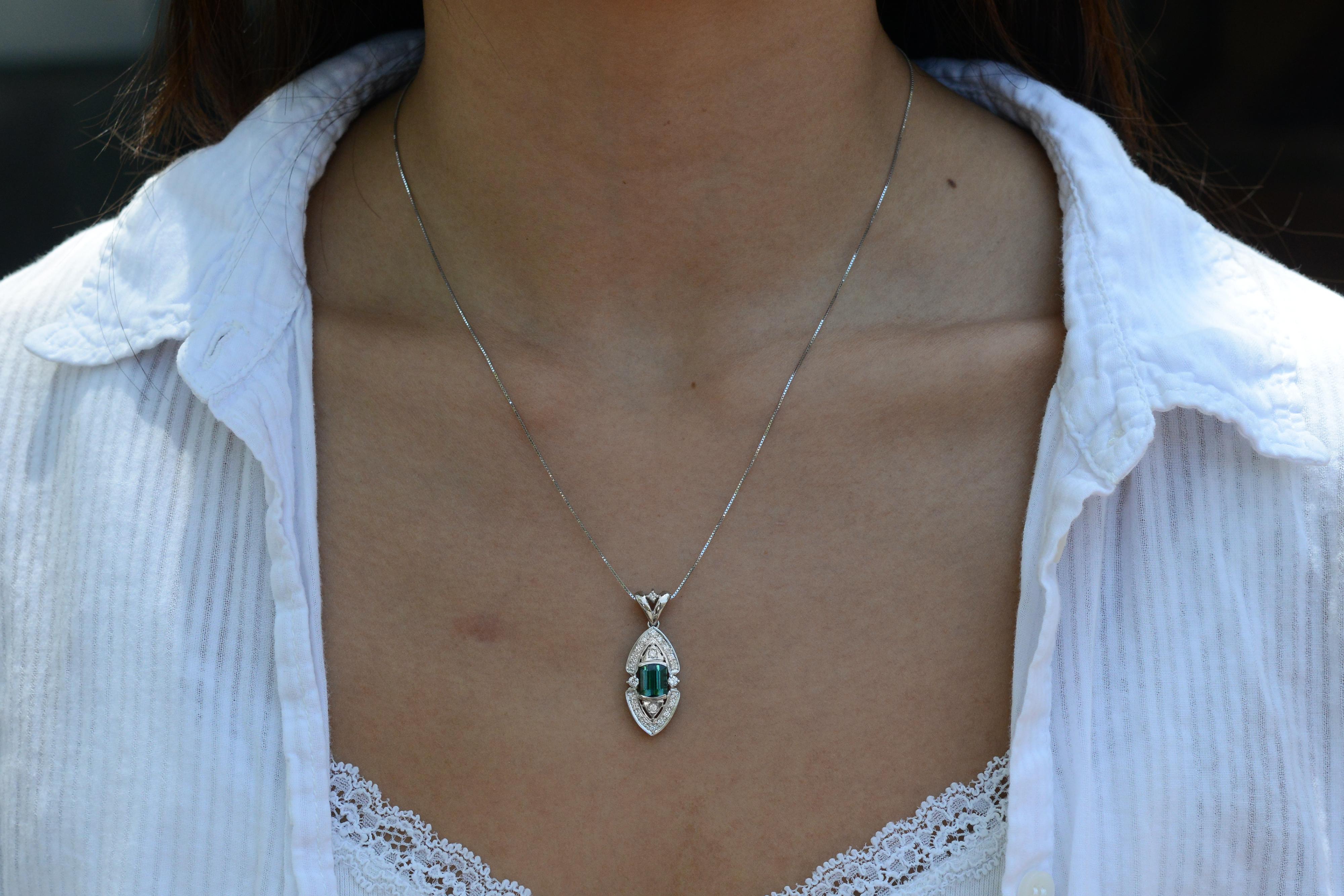 A lovely Art Nouveau inspired pendant, presenting a terrific tourmaline crafted in enduring platinum. With its unique shield design, it's the perfect way to adorn yourself in luxury for a unique and chic statement. Combining the beauty of a