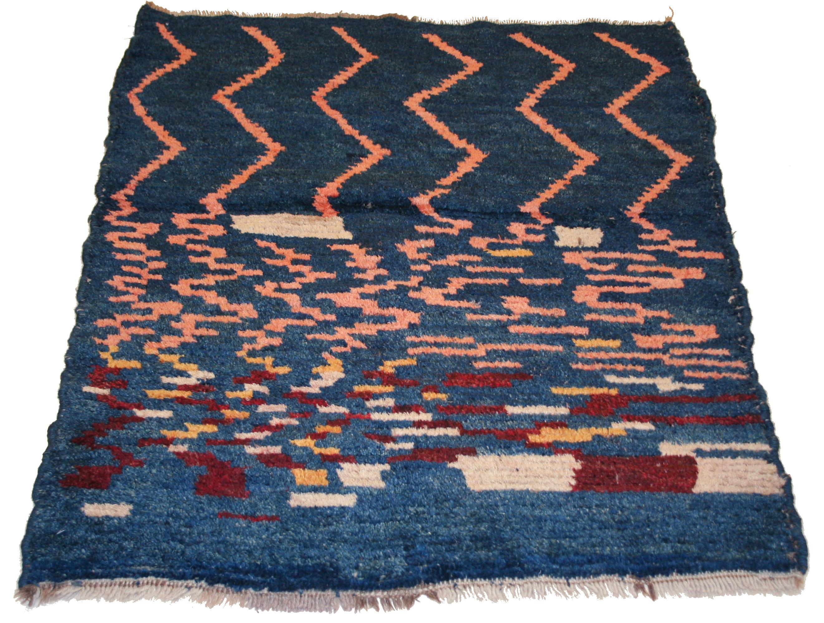 A charming small tribal rug distinguished by a pattern which starts out as a group of parallel vertical zig zag elements which suddenly break down in smaller units until they seem to almost dissolve and evolve into a naively drawn checkerboard