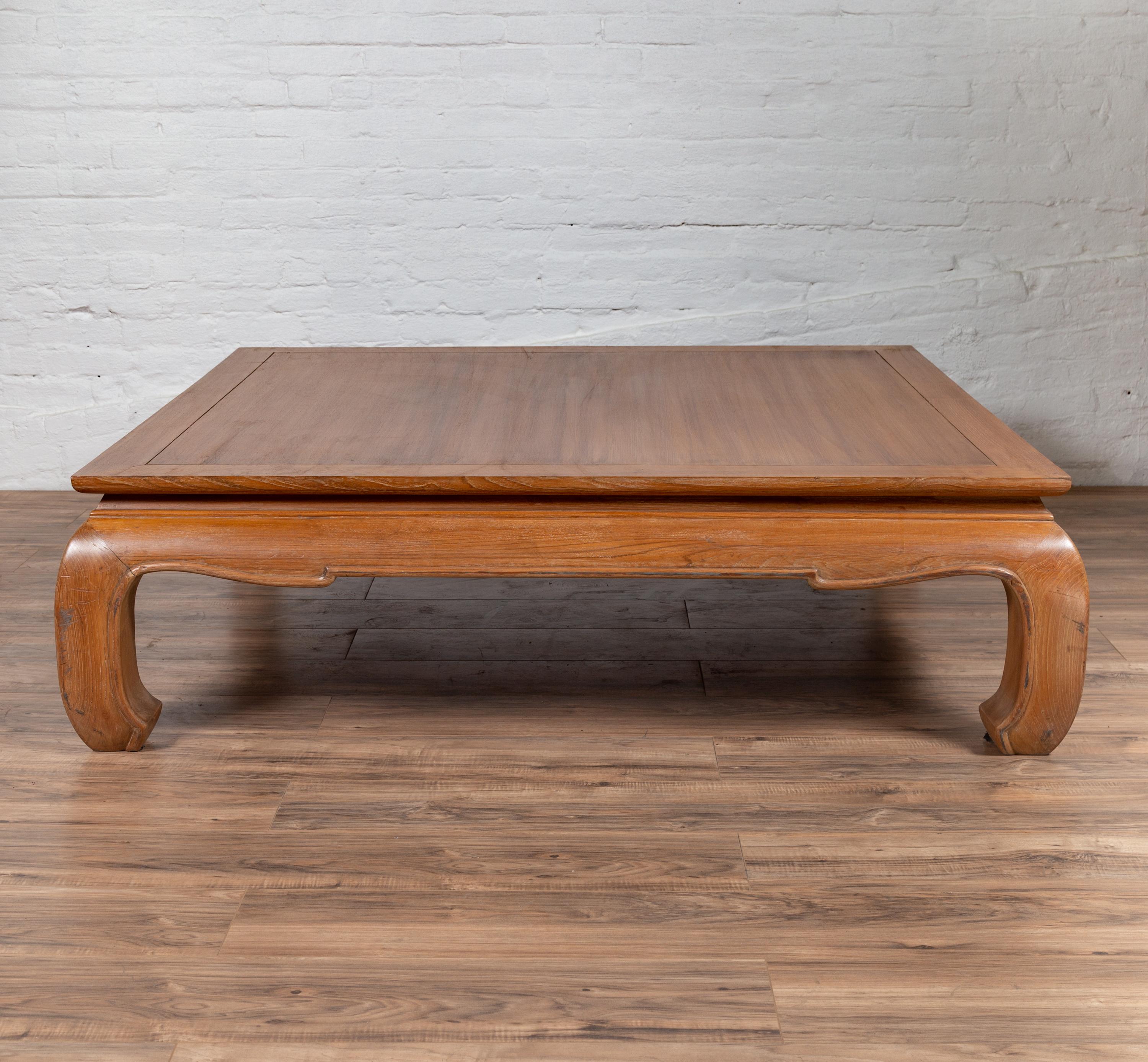 A vintage Indonesian teak wood coffee table from the mid-20th century, with natural bleached patina and bulging chow legs. Born in Indonesia during the midcentury period, this charming coffee table features a rectangular top with central board,