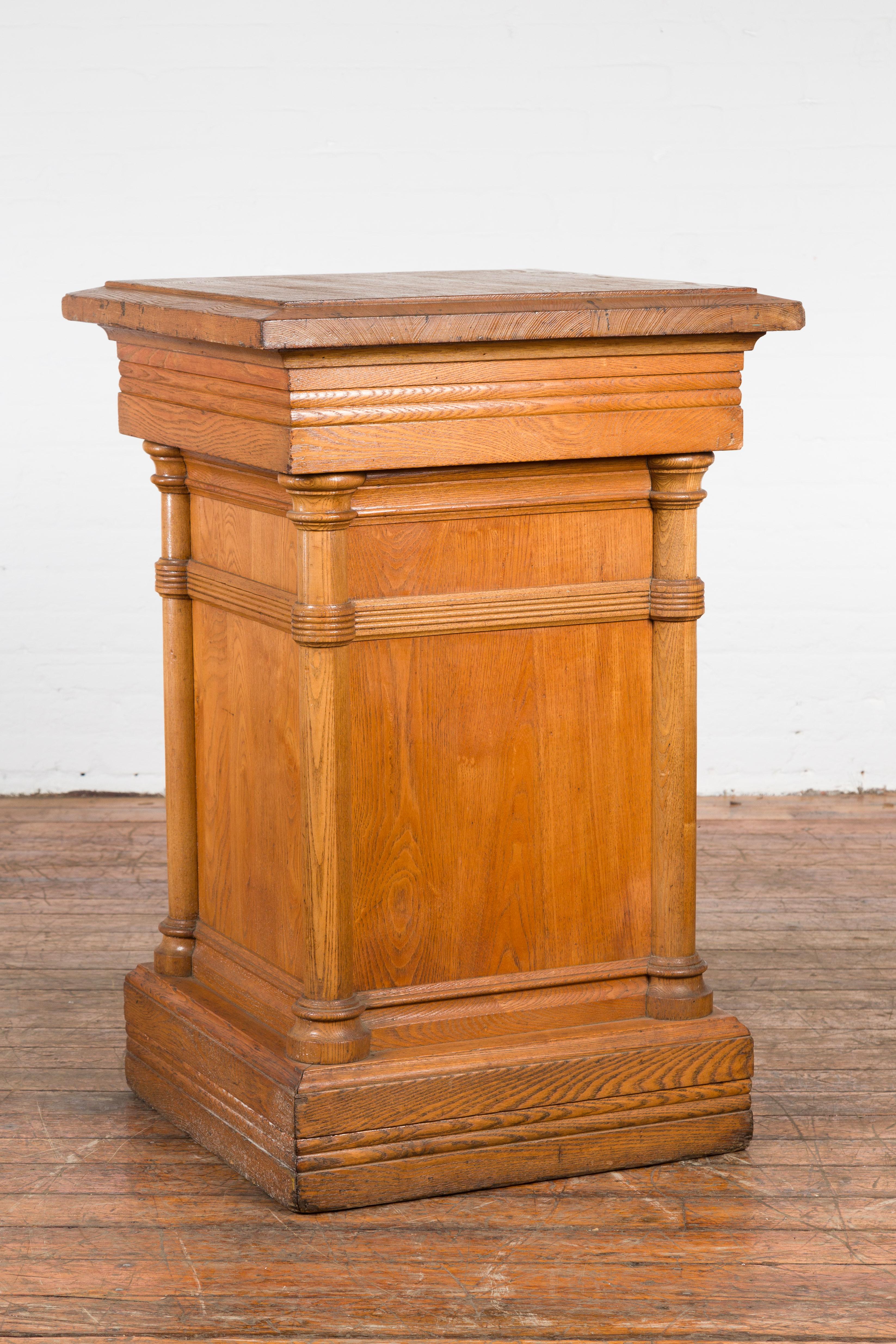 A vintage Indonesian nicely grained wooden pedestal from the mid 20th century, with Doric style semi-columns and natural patina. Created in Indonesia during the midcentury period, this wooden pedestal features a square top with beveled edges,